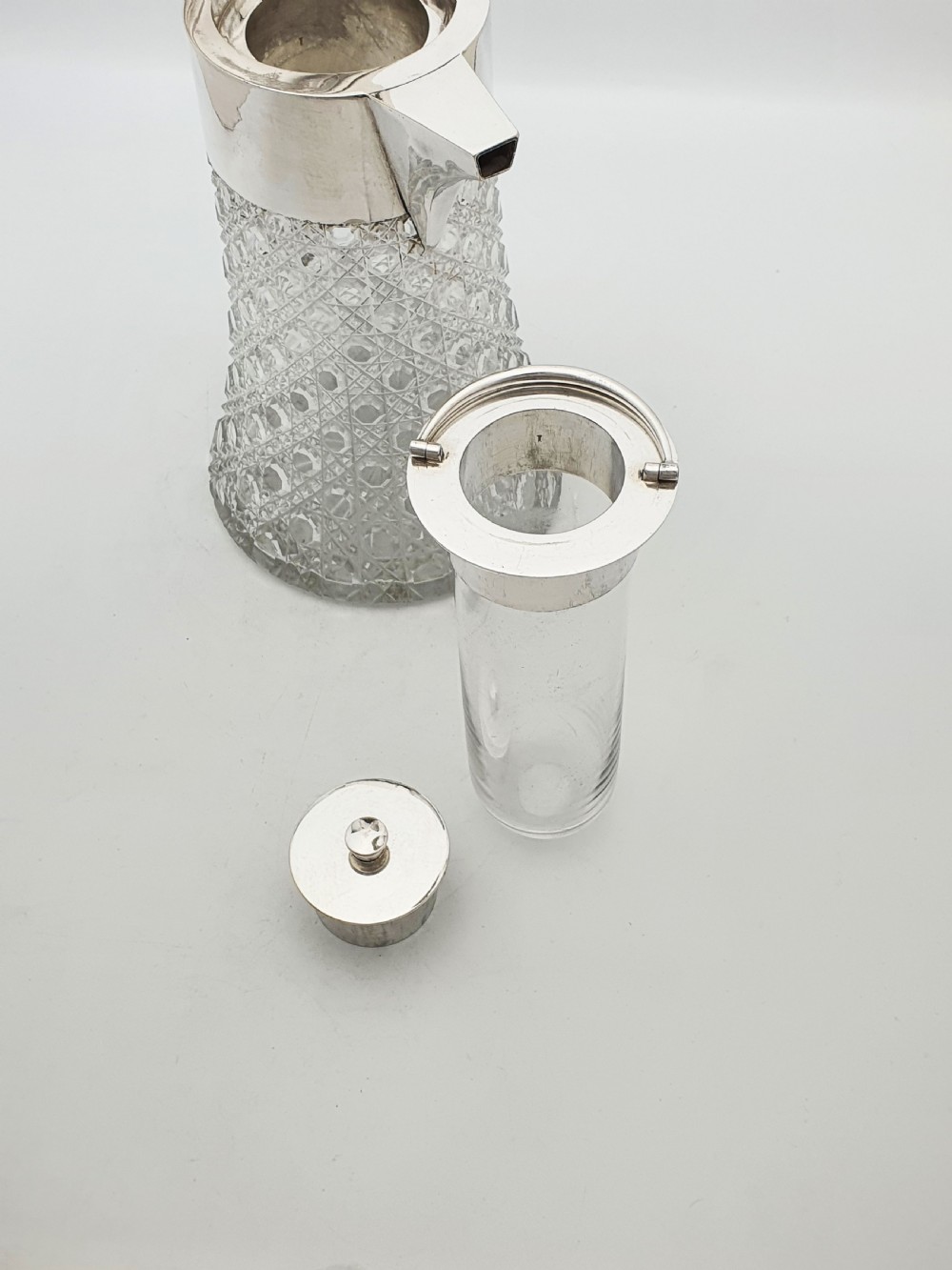 An antique Victorian cut glass lemonade jug featuring a silver-plated hinged lid and spout alongside its removable clear glass ice tube insert. View IV