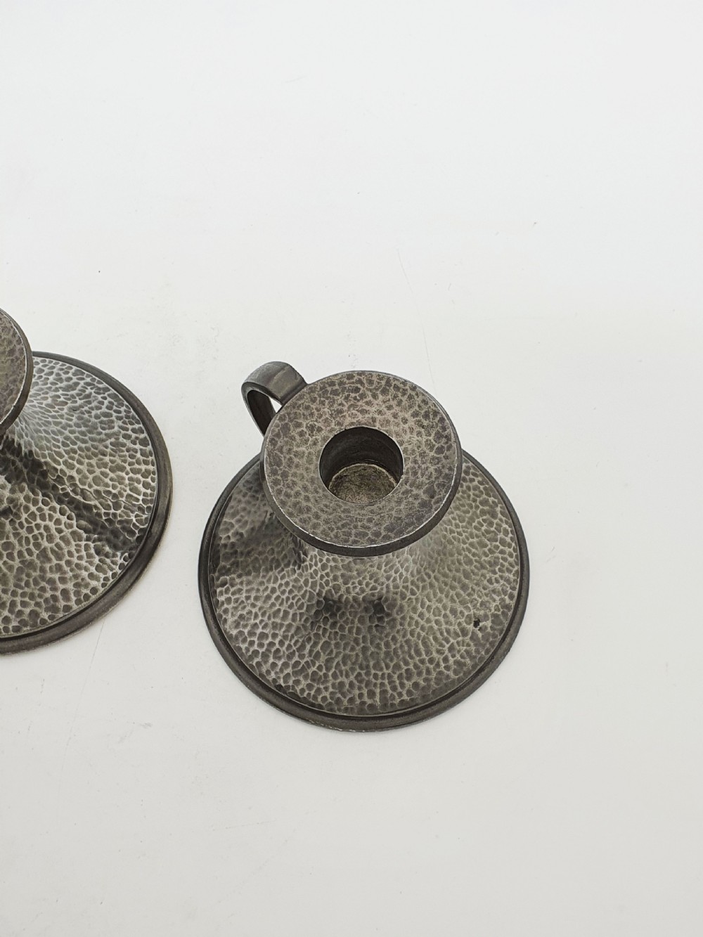 A pair of Arts and Crafts era flared pewter chambersticks with hand-hammered textures and curved side handles. View VII