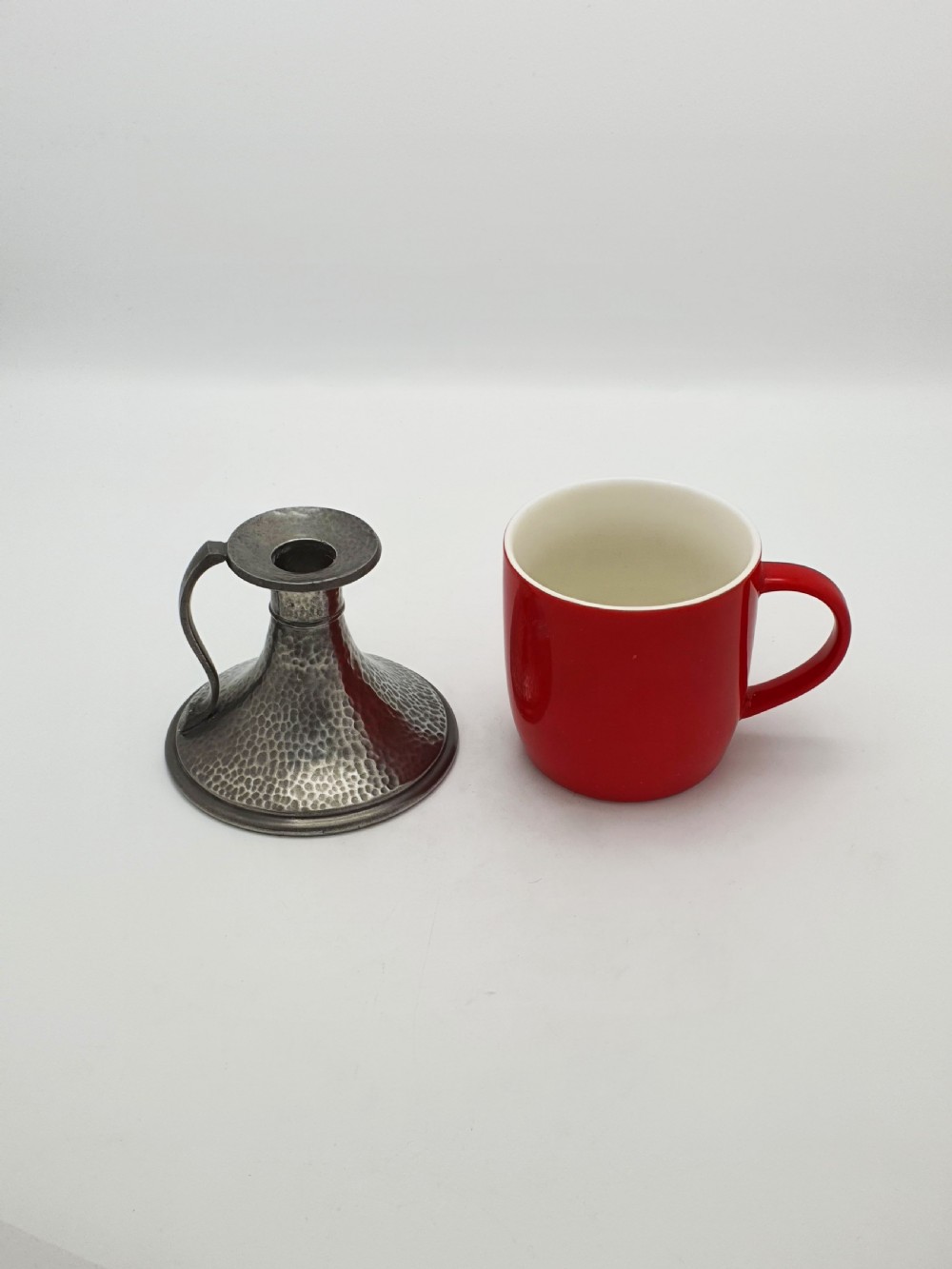 A pair of Arts and Crafts era flared pewter chambersticks with hand-hammered textures and curved side handles. View IX