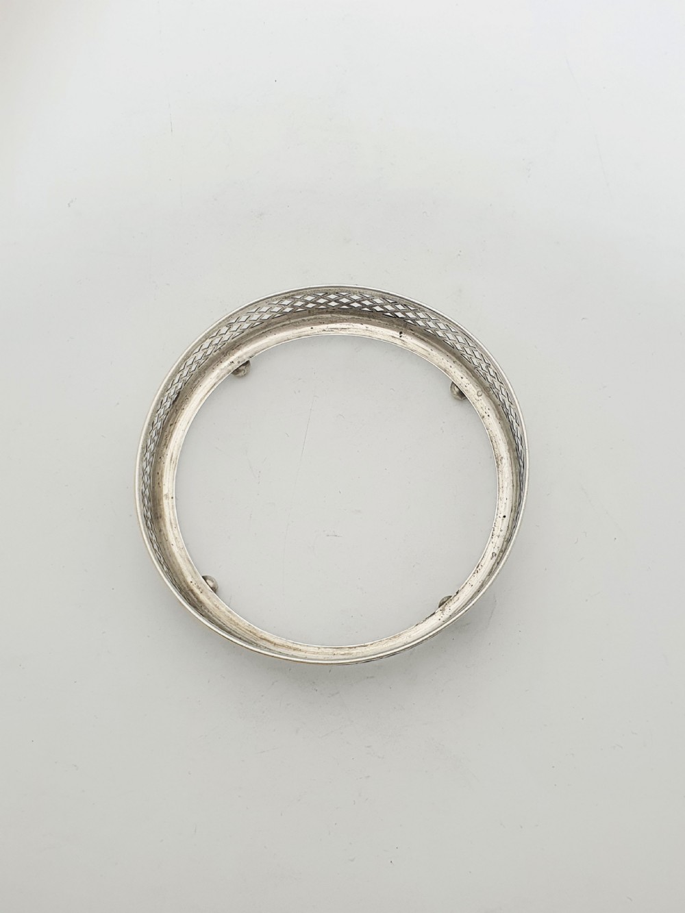 A circular sterling silver dish with a pierced lattice pattern, raised on small ball feet, fitted with a clear glass insert. View V