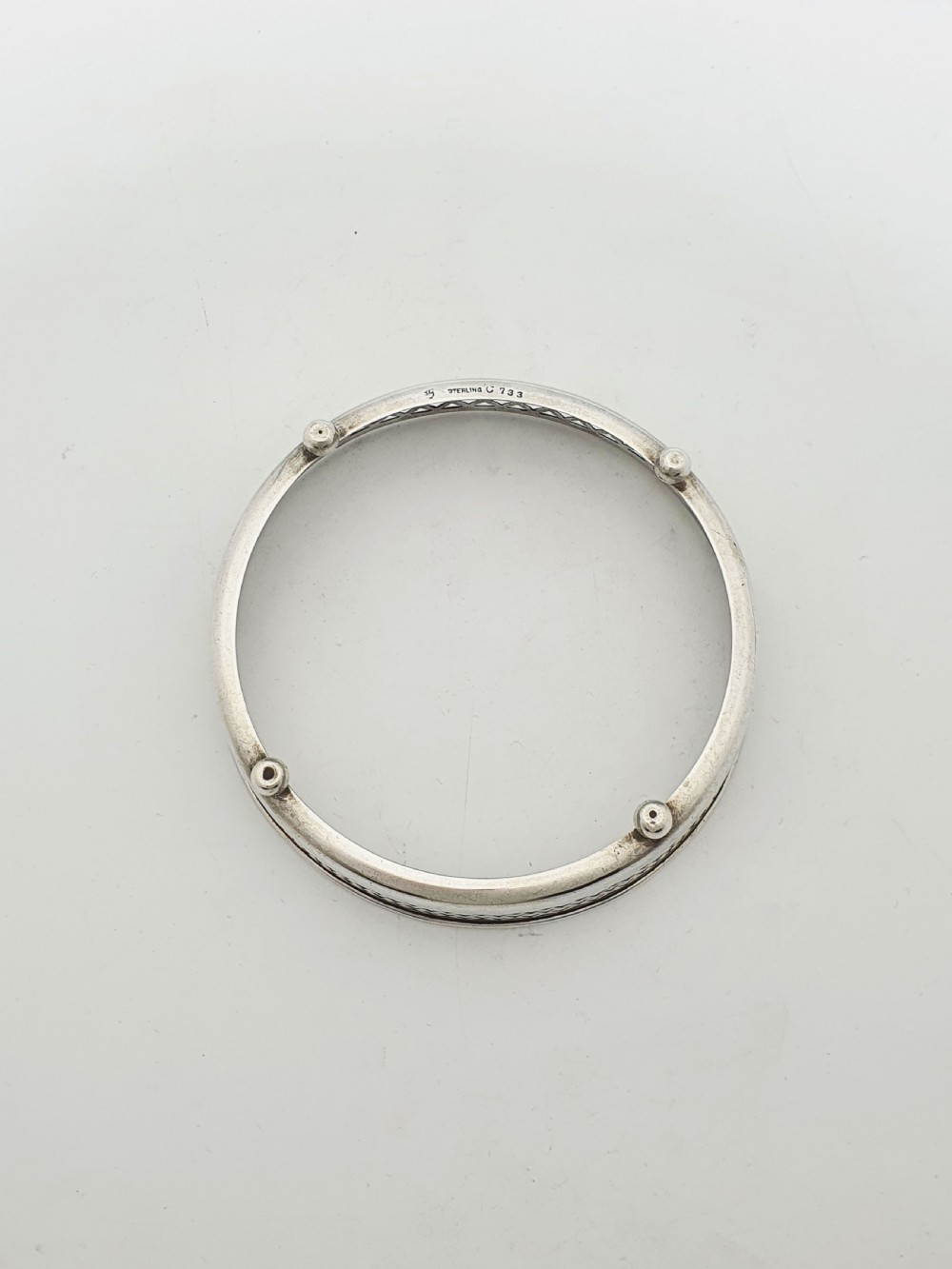 A circular sterling silver dish with a pierced lattice pattern, raised on small ball feet, fitted with a clear glass insert. View VII