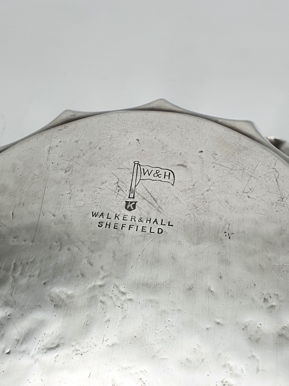 An oval silver plate serving dish featuring intricate floral engravings in the centre and a fluted scalloped outer rim. View VI