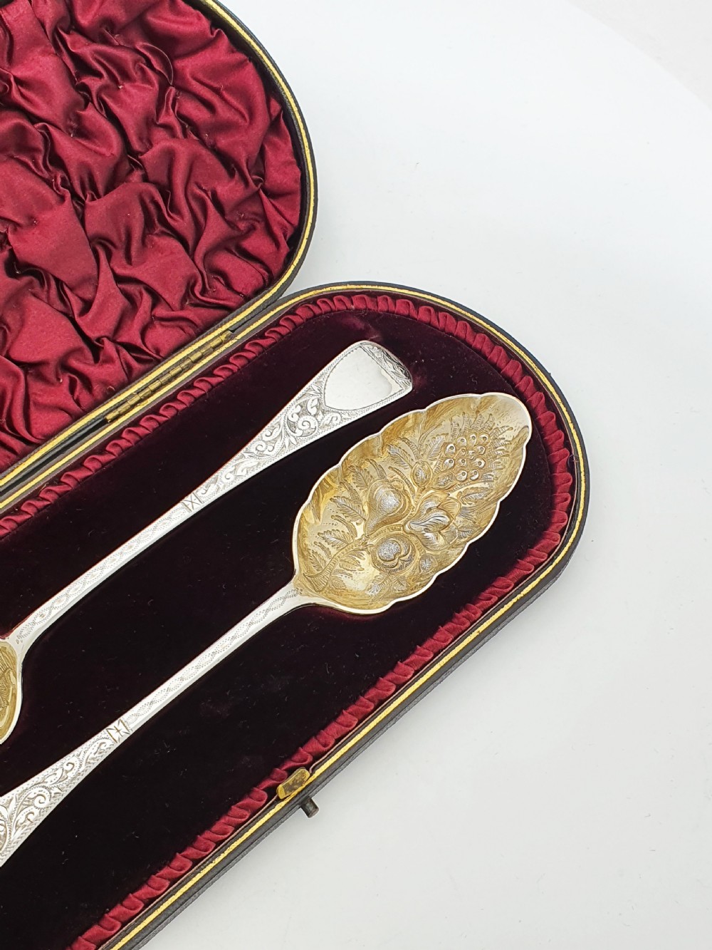 A pair of Victorian sterling silver berry spoons with embossed gilt fruit bowls and engraved handles, presented in a fitted velvet-lined case. View III