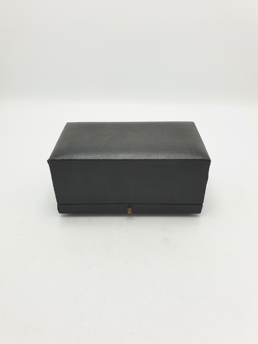 A pair of engraved sterling silver napkin rings with circular cartouches resting inside a dark blue velvet-lined presentation box. View IX