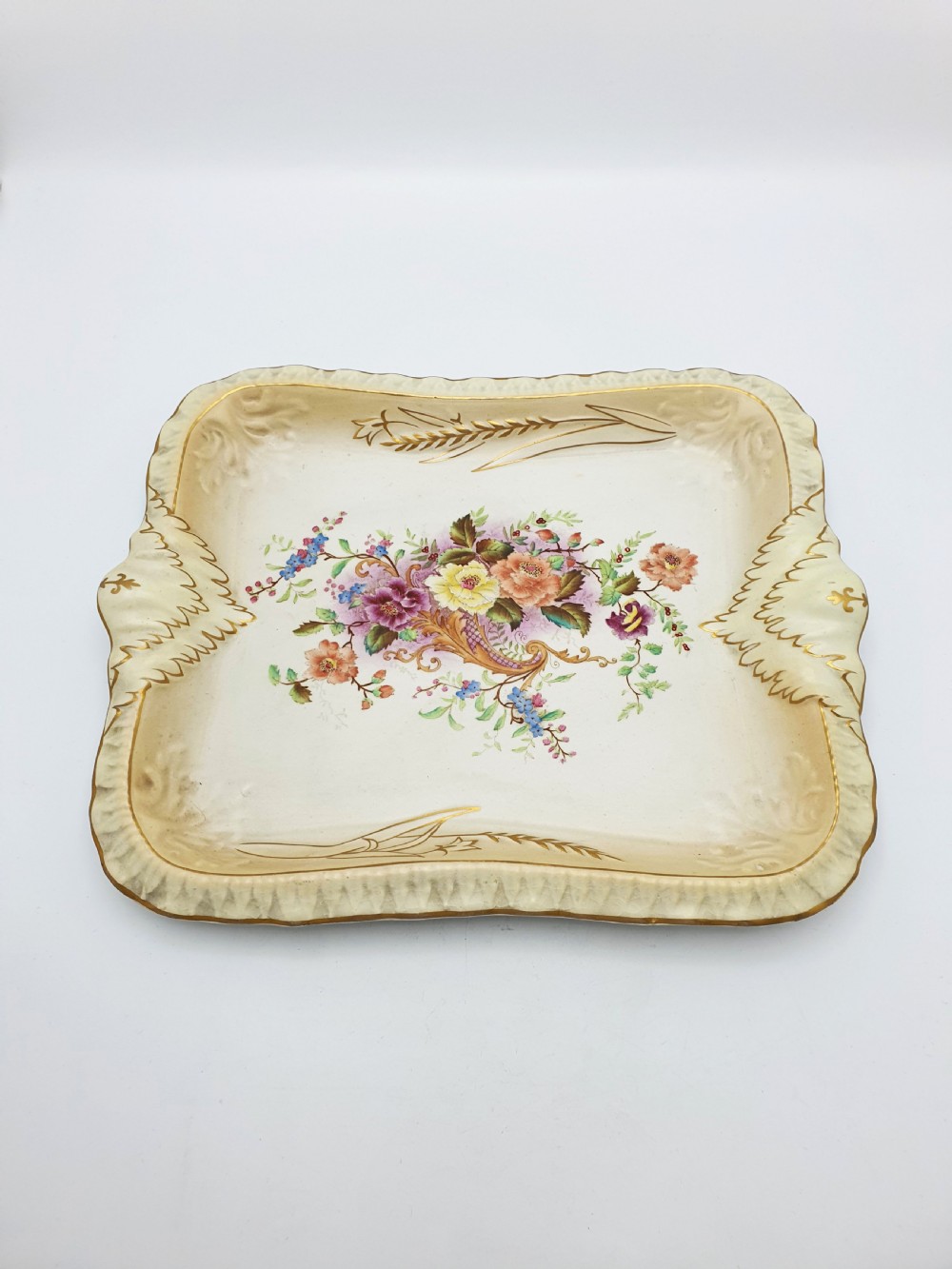 A rectangular cream ceramic tray with a central floral motif and gilded relief border. View II