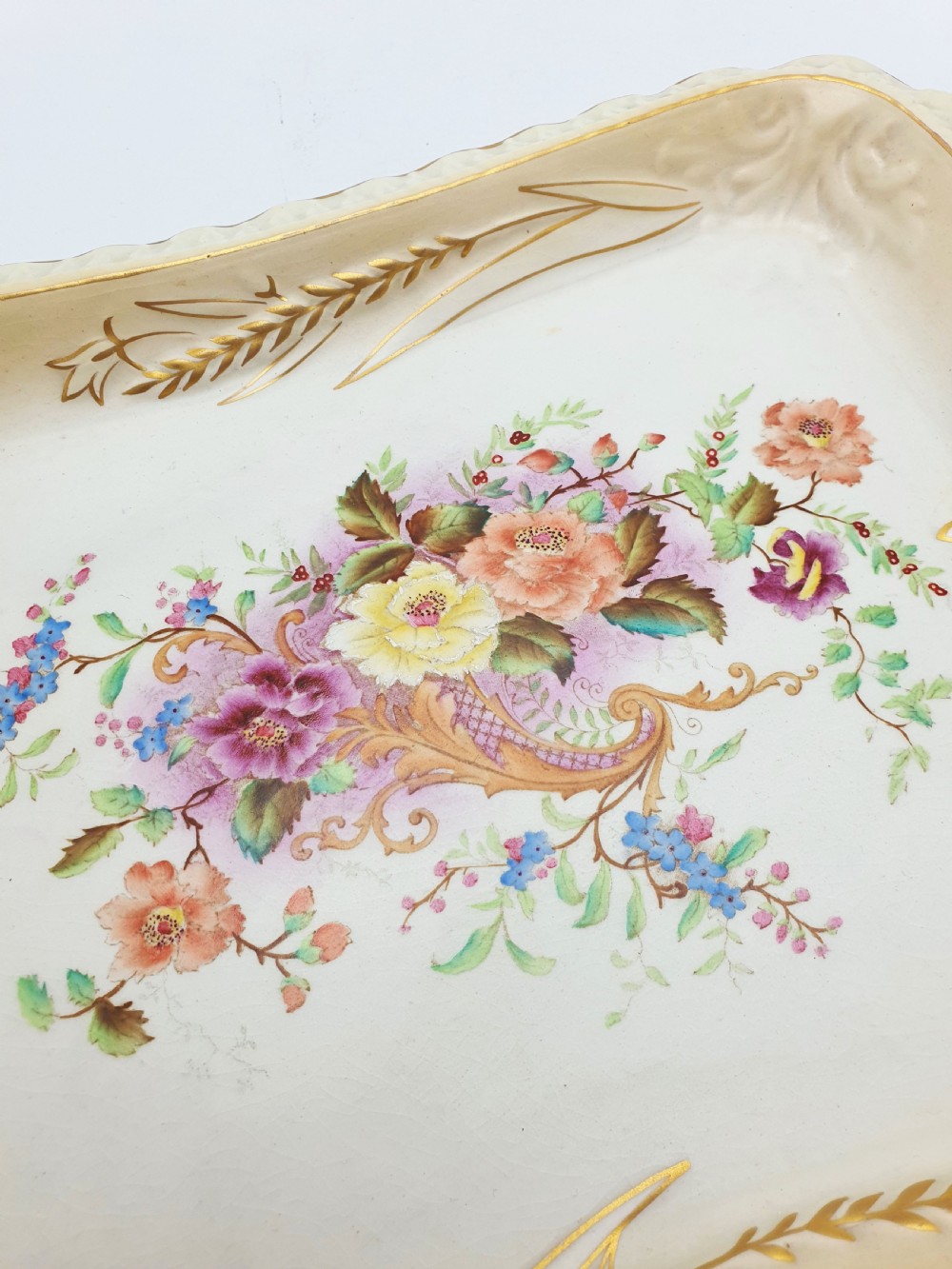 A rectangular cream ceramic tray with a central floral motif and gilded relief border. View VI