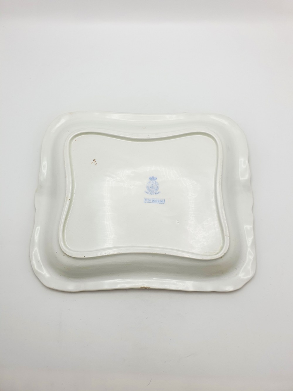 A rectangular cream ceramic tray with a central floral motif and gilded relief border. View VII
