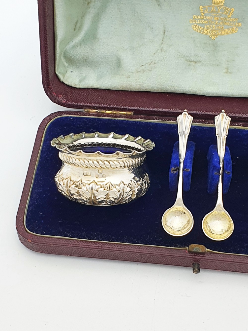 A pair of Victorian sterling silver open salt cellars with repousse leaf decoration and matching silver spoons in a velvet-lined maroon fitted box. View II