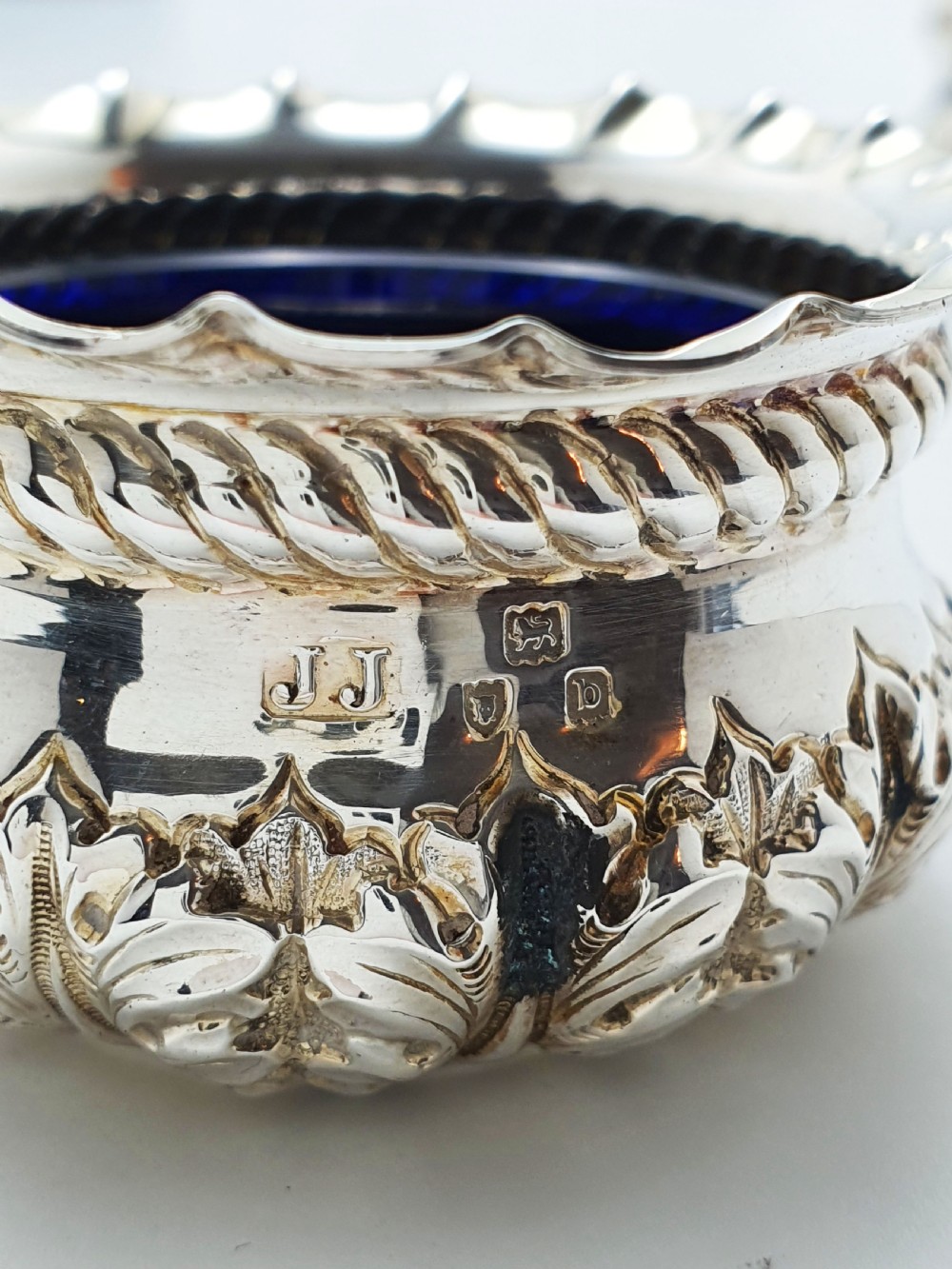 A pair of Victorian sterling silver open salt cellars with repousse leaf decoration and matching silver spoons in a velvet-lined maroon fitted box. View IX