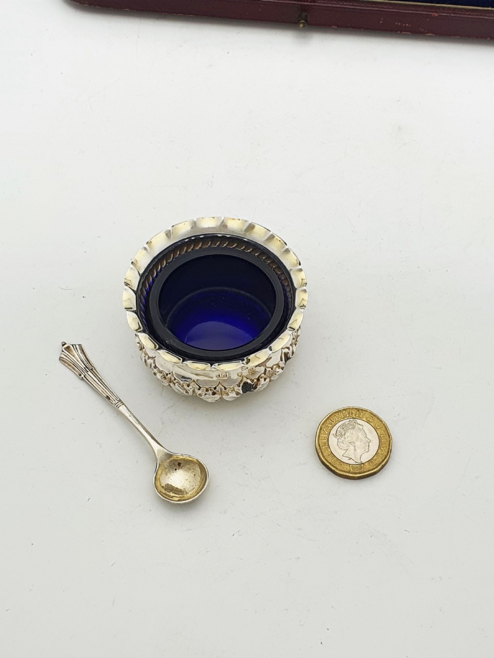 A pair of Victorian sterling silver open salt cellars with repousse leaf decoration and matching silver spoons in a velvet-lined maroon fitted box. View X