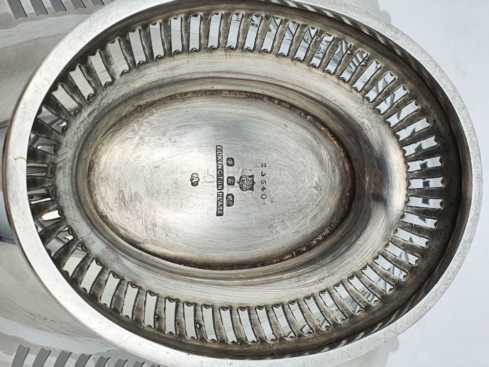 A George V silver-plated oval basket featuring a pierced border, relief rococo scroll edging, and a central hinged swing handle. View VII