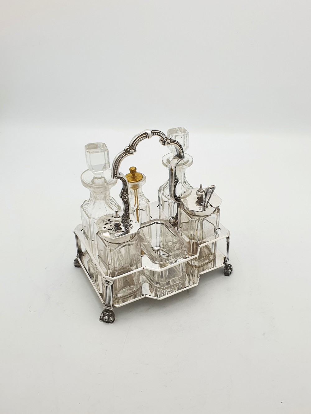 A Victorian silver-plated bachelor cruet set featuring an ornate handle frame holding multiple cut-glass condiment bottles.