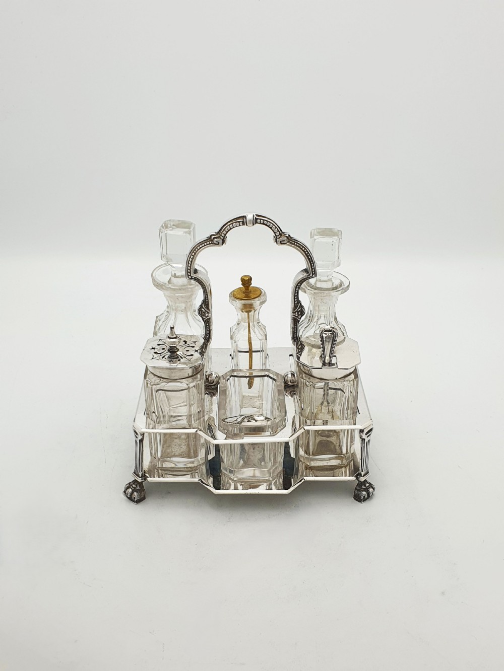 A Victorian silver-plated bachelor cruet set featuring an ornate handle frame holding multiple cut-glass condiment bottles. View II