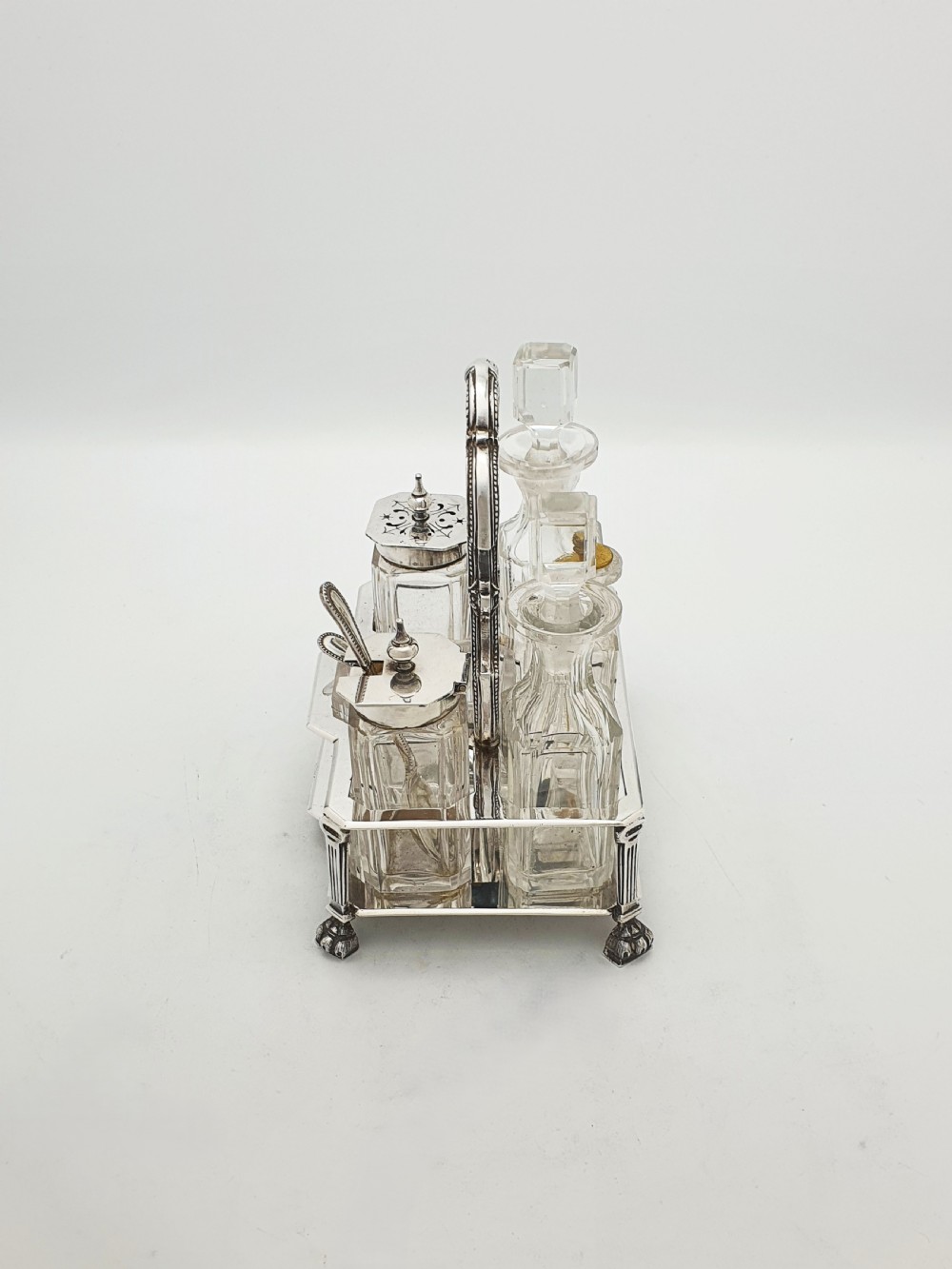 A Victorian silver-plated bachelor cruet set featuring an ornate handle frame holding multiple cut-glass condiment bottles. View III