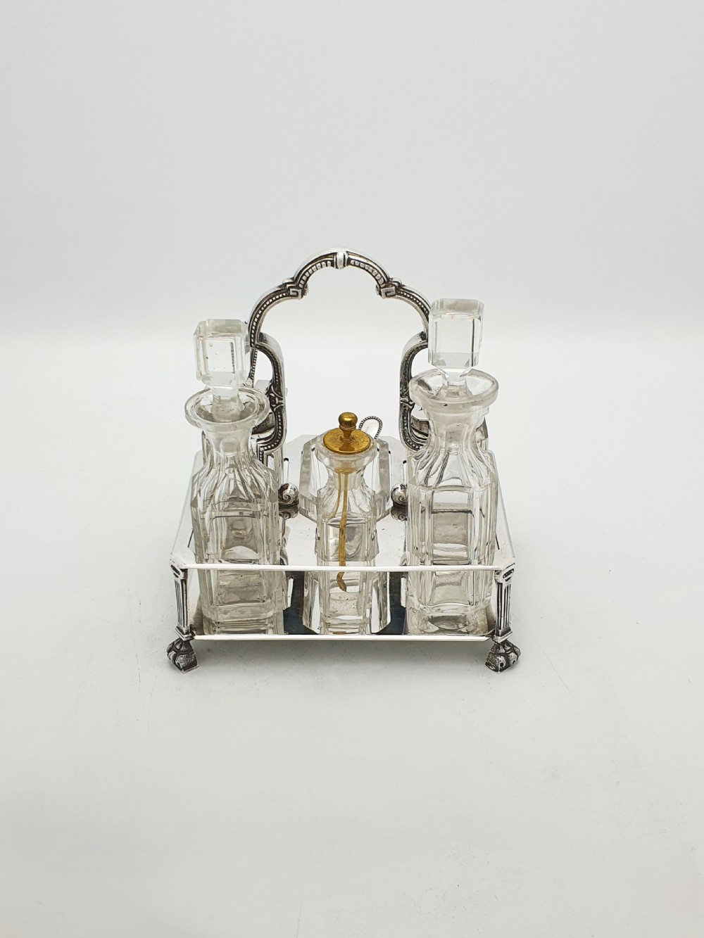 A Victorian silver-plated bachelor cruet set featuring an ornate handle frame holding multiple cut-glass condiment bottles. View IV