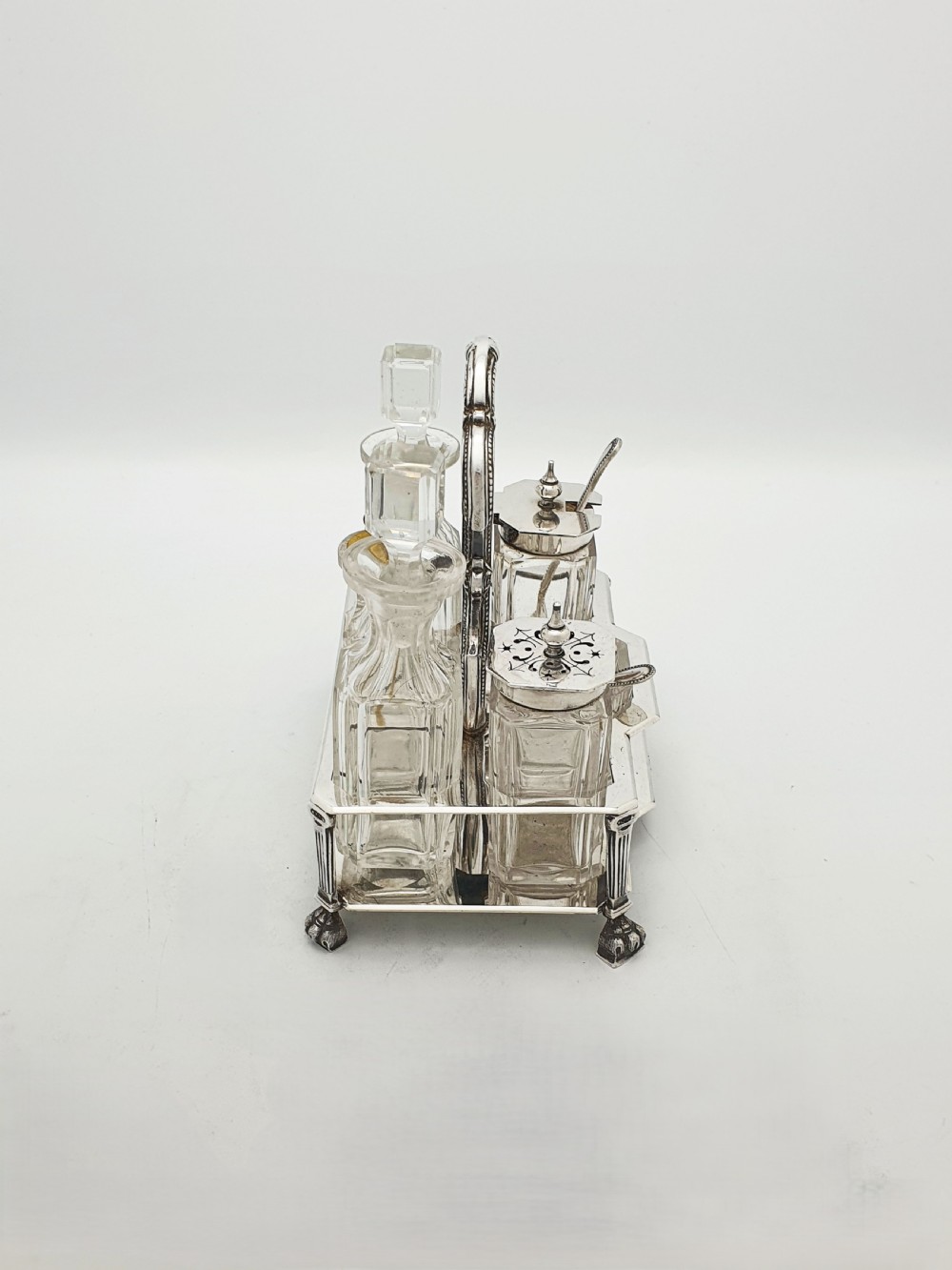 A Victorian silver-plated bachelor cruet set featuring an ornate handle frame holding multiple cut-glass condiment bottles. View V