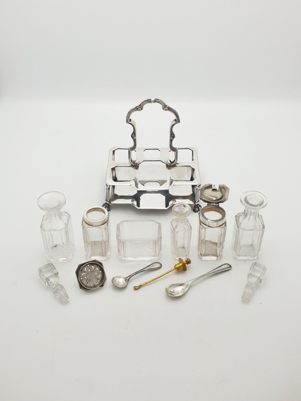 A Victorian silver-plated bachelor cruet set featuring an ornate handle frame holding multiple cut-glass condiment bottles. View VII