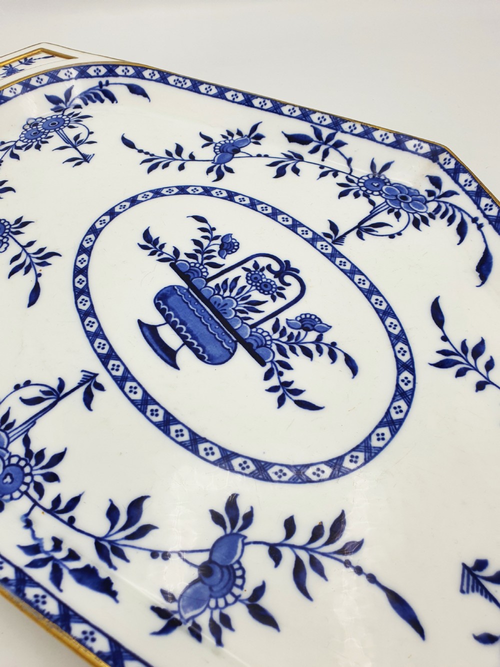 An elongated diamond-shaped white porcelain tray decorated with blue floral transfers, a central floral basket motif, and gilded handles. View II