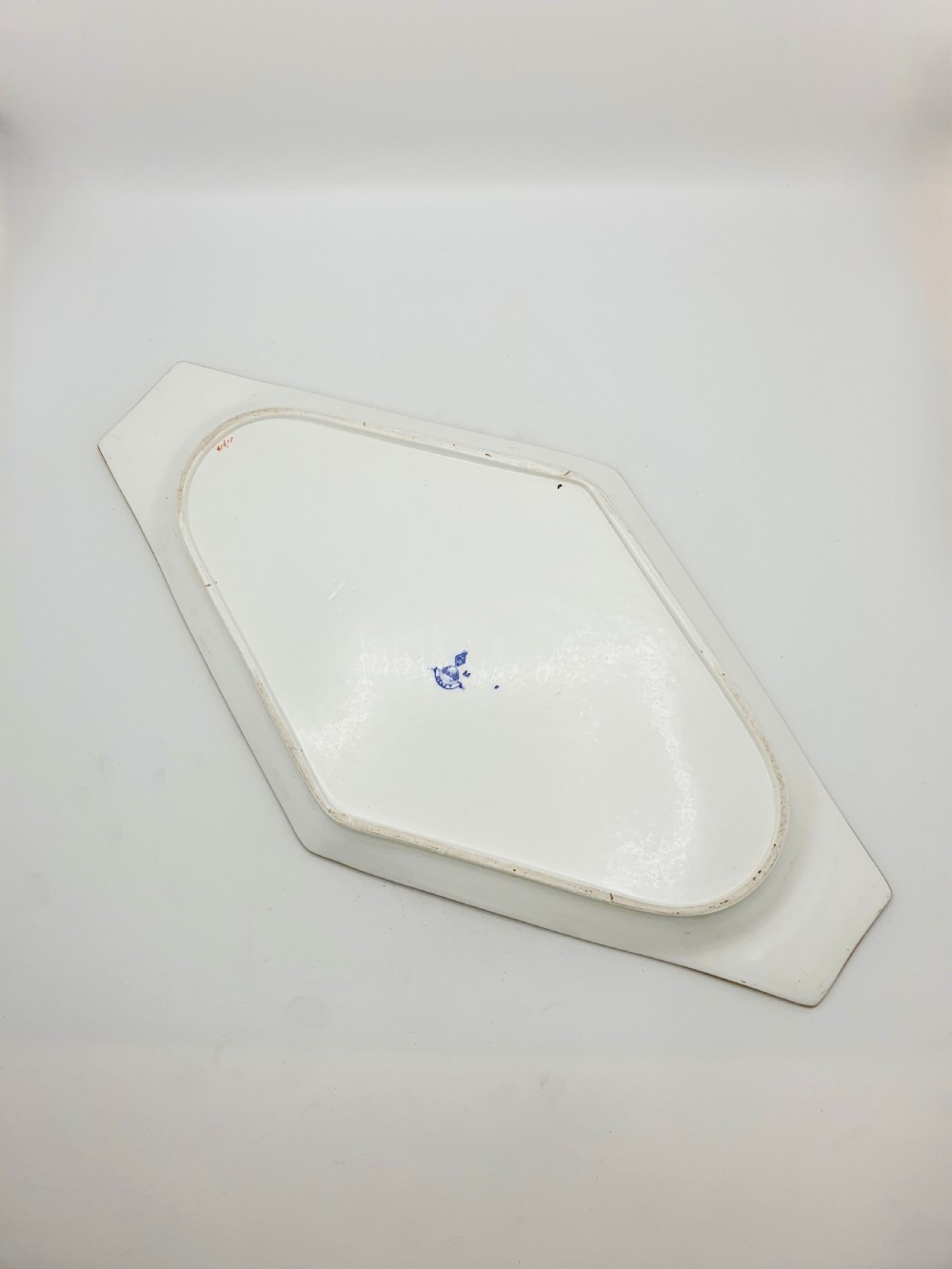 An elongated diamond-shaped white porcelain tray decorated with blue floral transfers, a central floral basket motif, and gilded handles. View IV