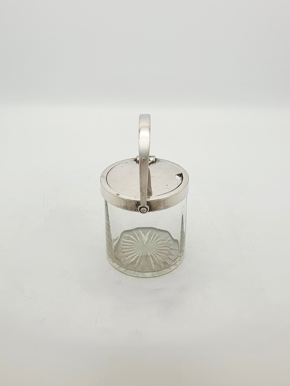 An antique cut glass condiment jar featuring a hallmarked sterling silver rim, swing handle, and hinged lid. View V