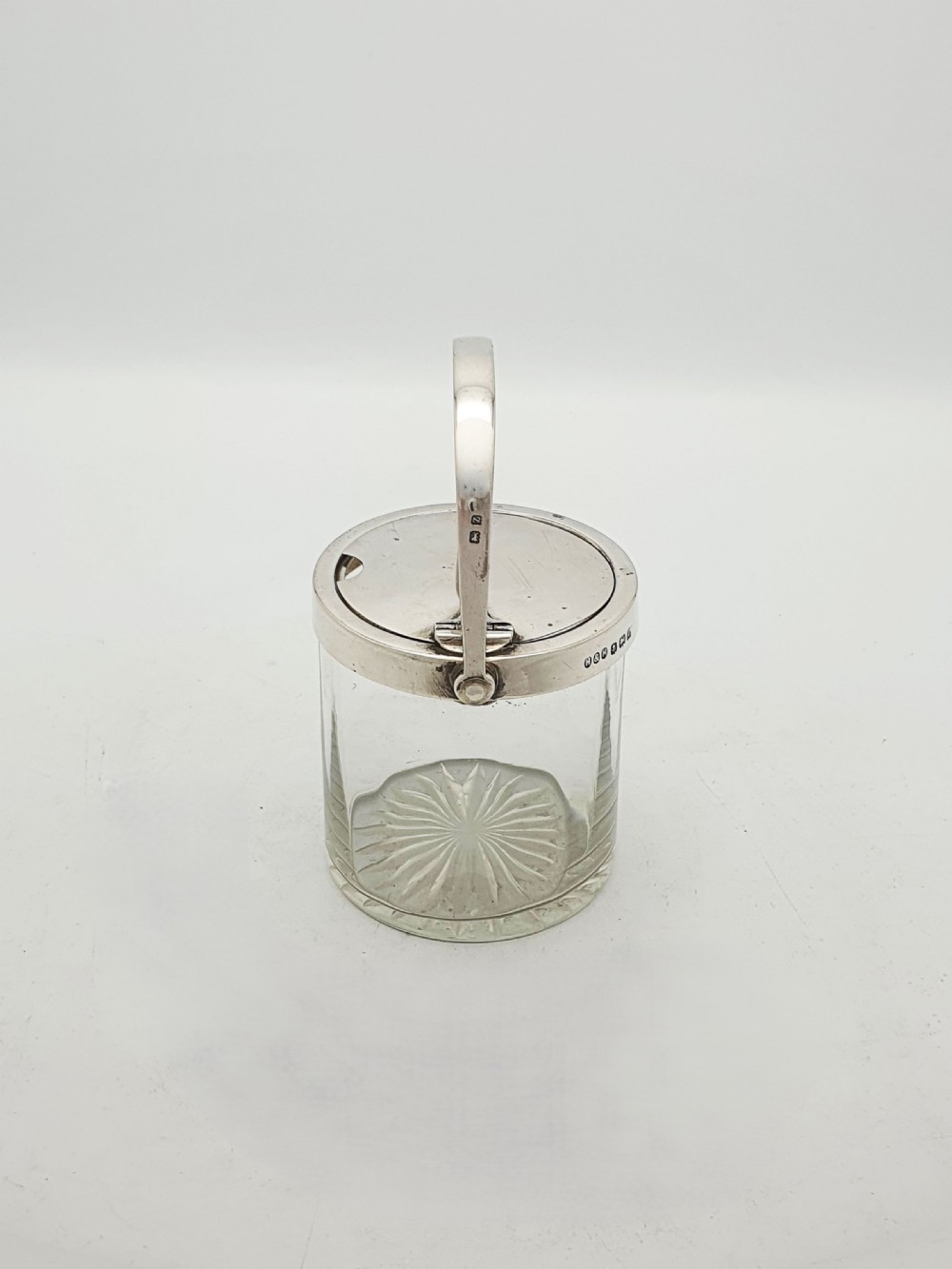 An antique cut glass condiment jar featuring a hallmarked sterling silver rim, swing handle, and hinged lid. View VI