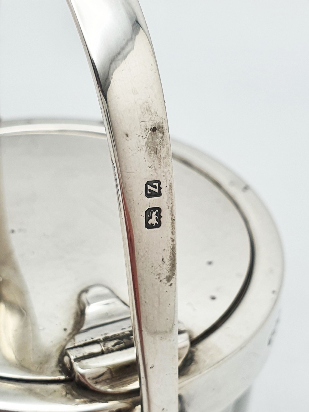 An antique cut glass condiment jar featuring a hallmarked sterling silver rim, swing handle, and hinged lid. View IX