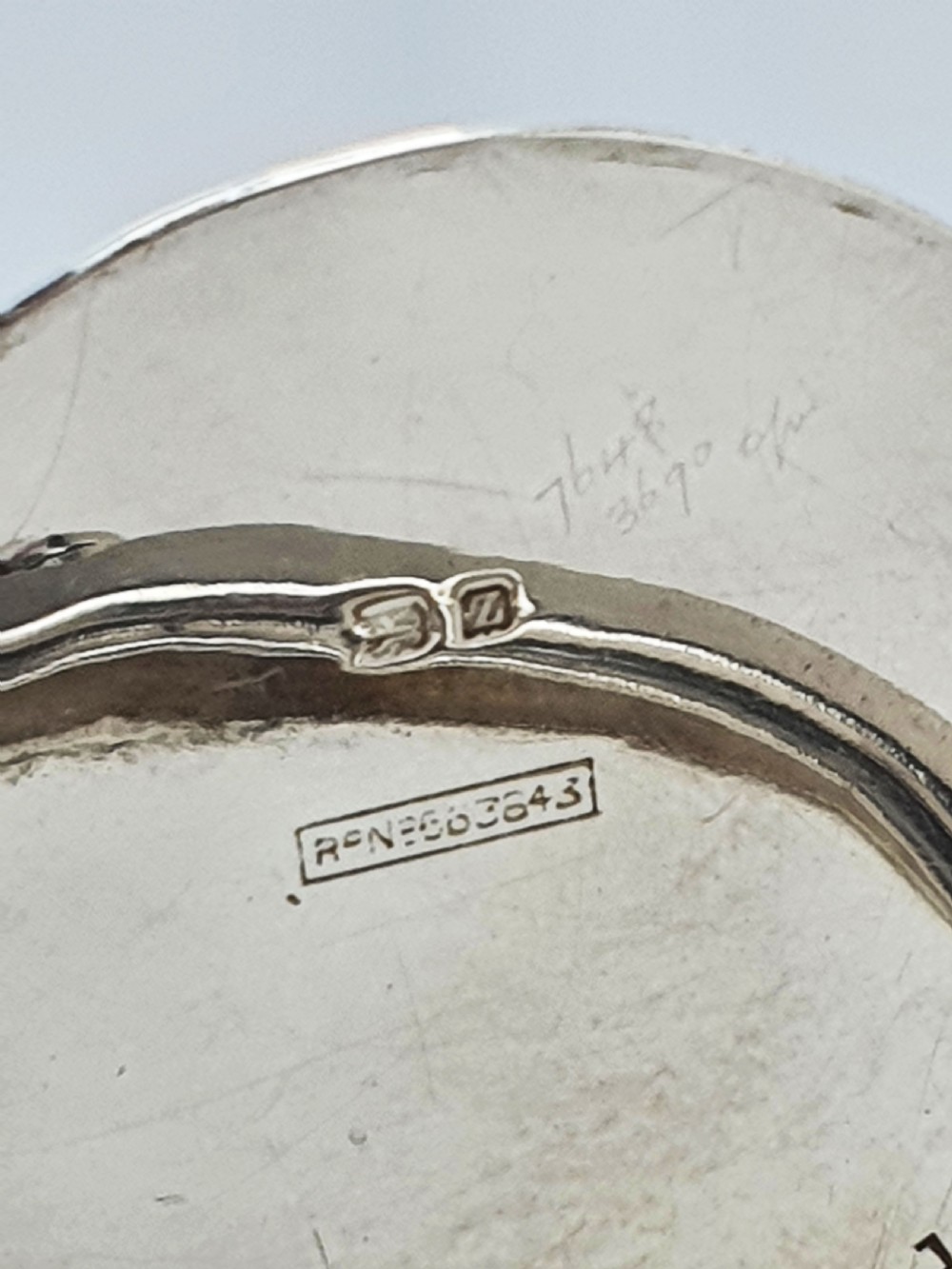 An antique cut glass condiment jar featuring a hallmarked sterling silver rim, swing handle, and hinged lid. View X