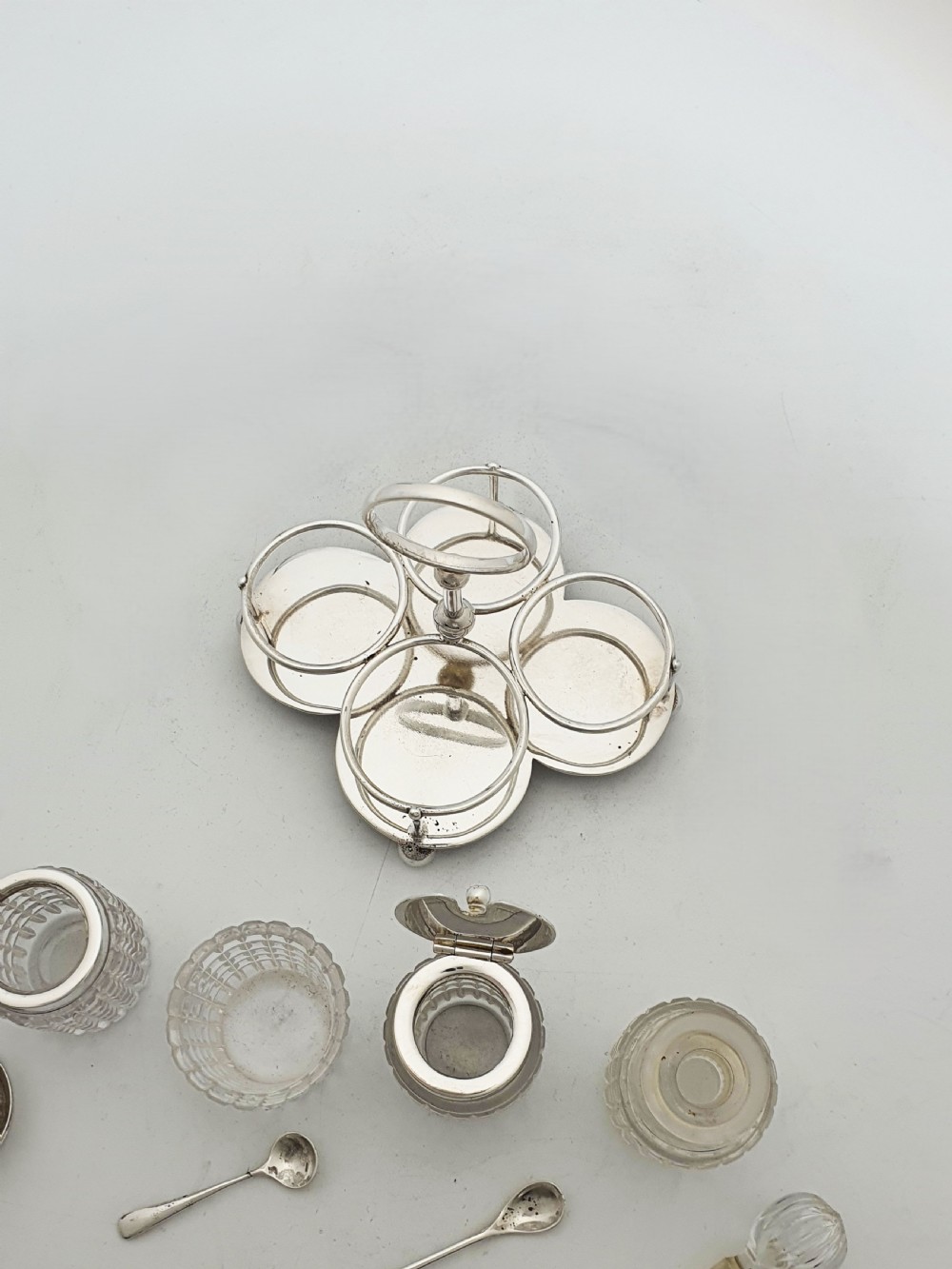 An antique silver-plated condiment caddy holding four faceted cut-glass bottles and pots with silver lids. View VIII