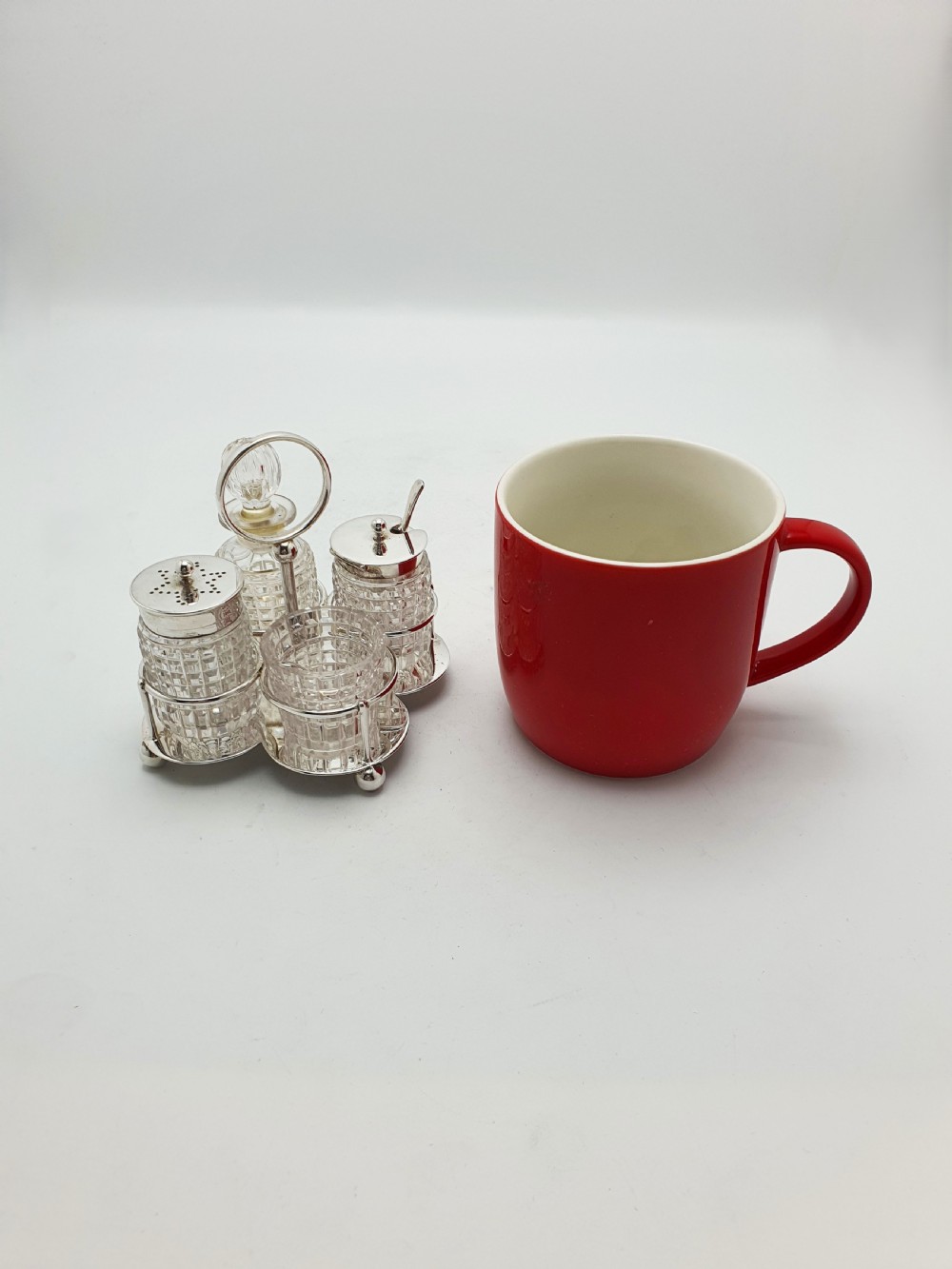 An antique silver-plated condiment caddy holding four faceted cut-glass bottles and pots with silver lids. View IX