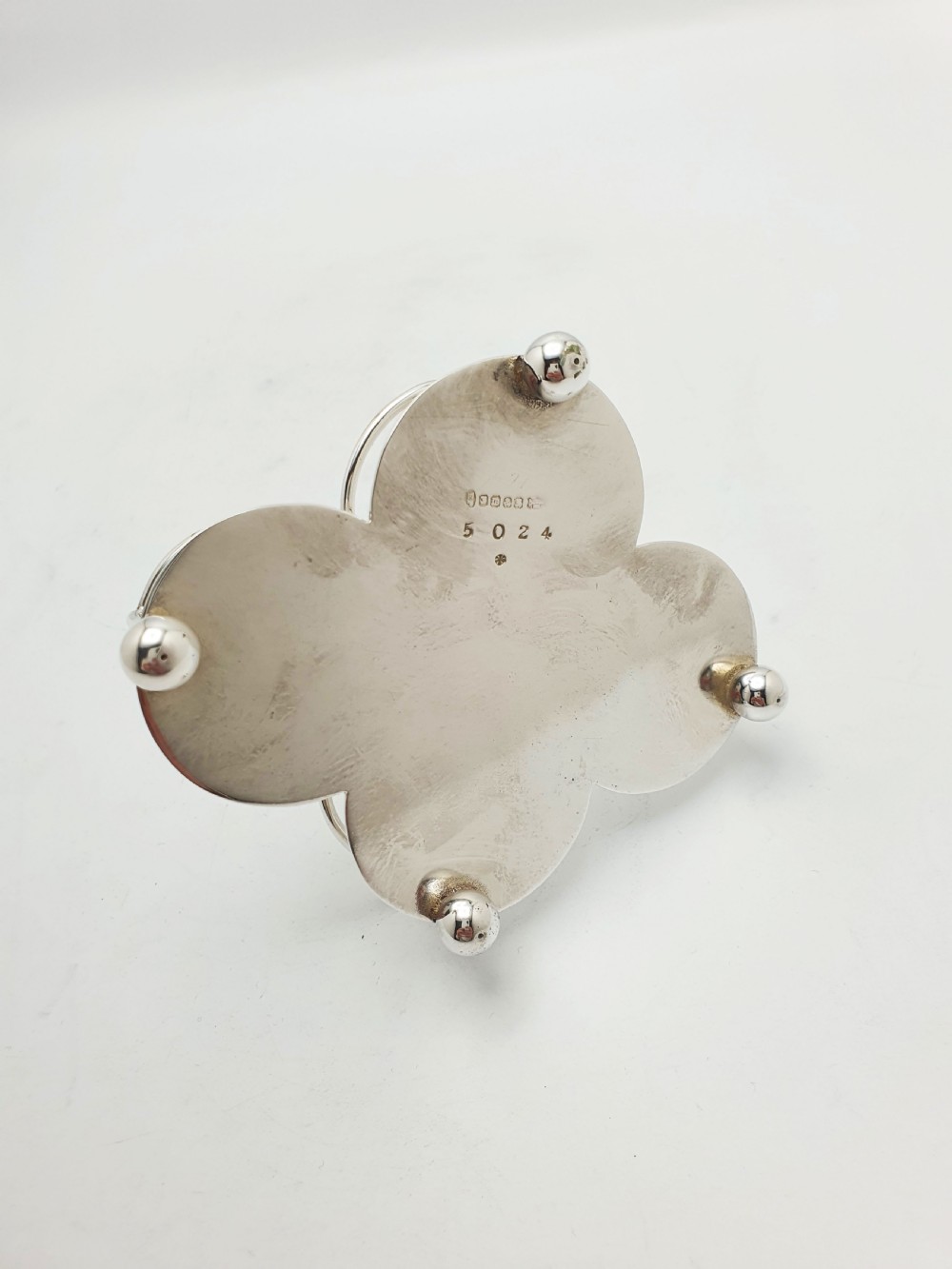 An antique silver-plated condiment caddy holding four faceted cut-glass bottles and pots with silver lids. View X