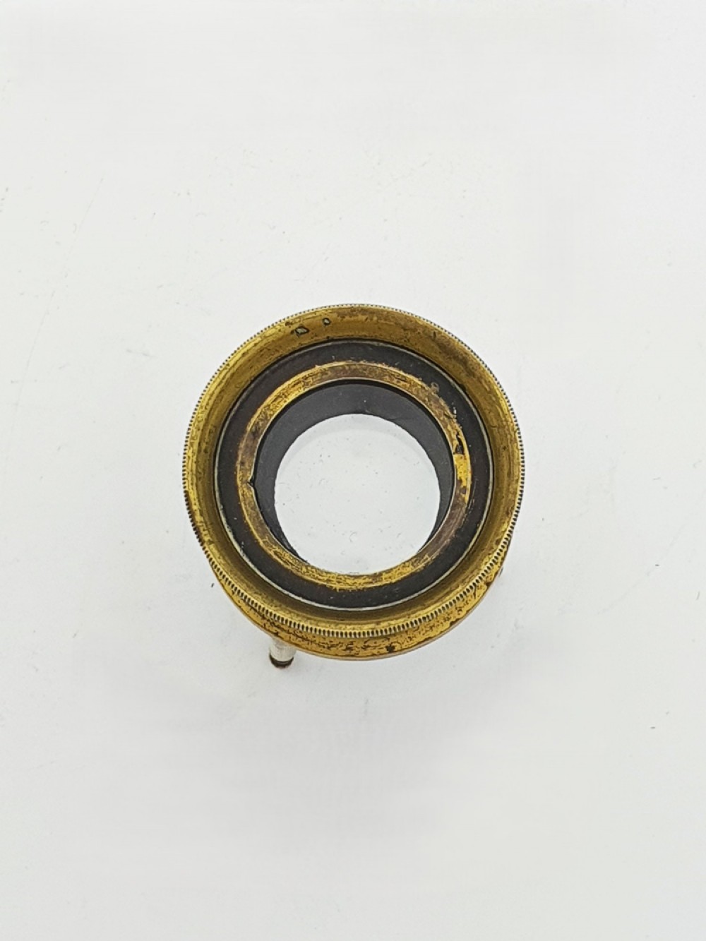 An antique Edwardian circular solid brass desk magnifying loupe resting on three turned tripod feet. View II