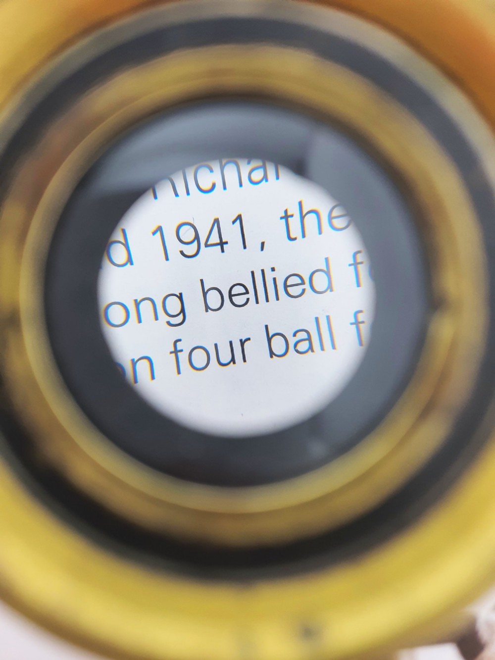 An antique Edwardian circular solid brass desk magnifying loupe resting on three turned tripod feet. View IV