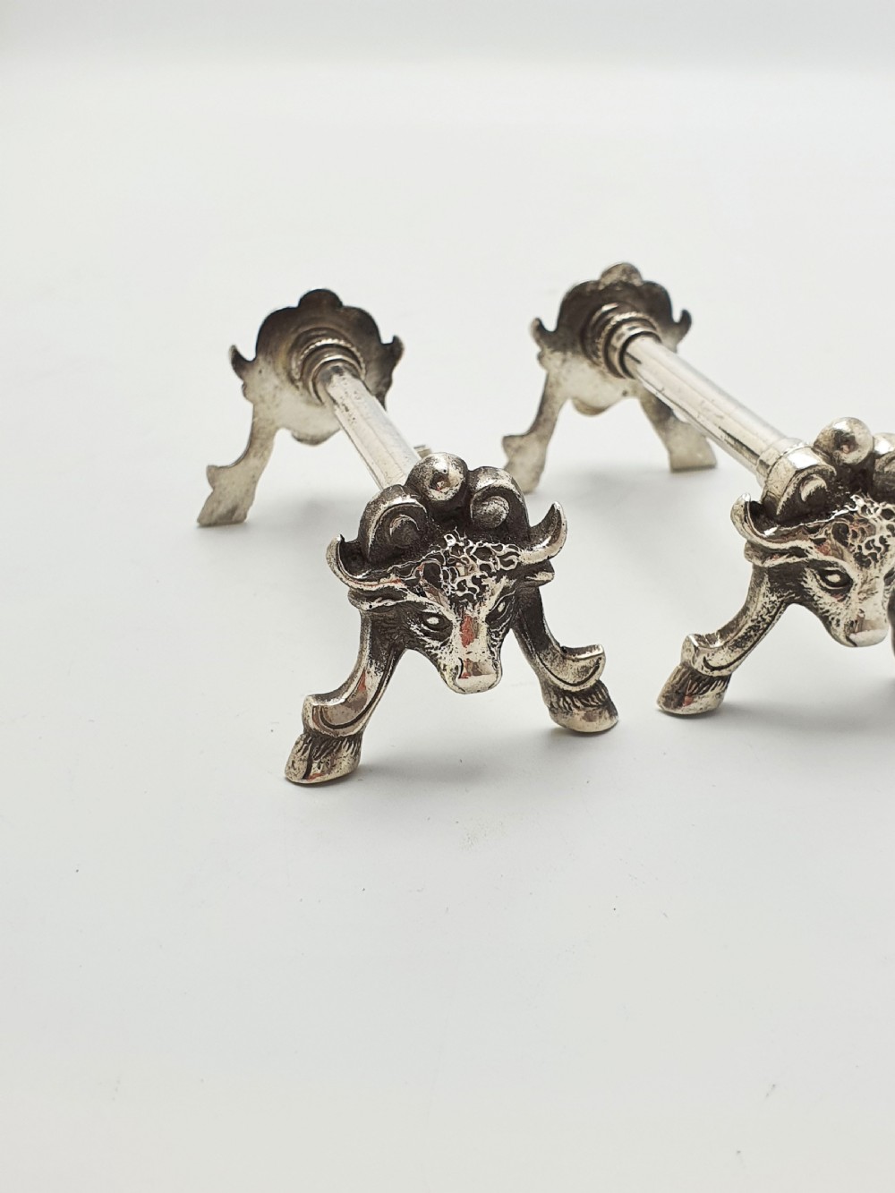 A pair of Victorian silver-plated knife rests featuring detailed cast bull head terminals with hoof legs supporting a cylindrical bar. View IV