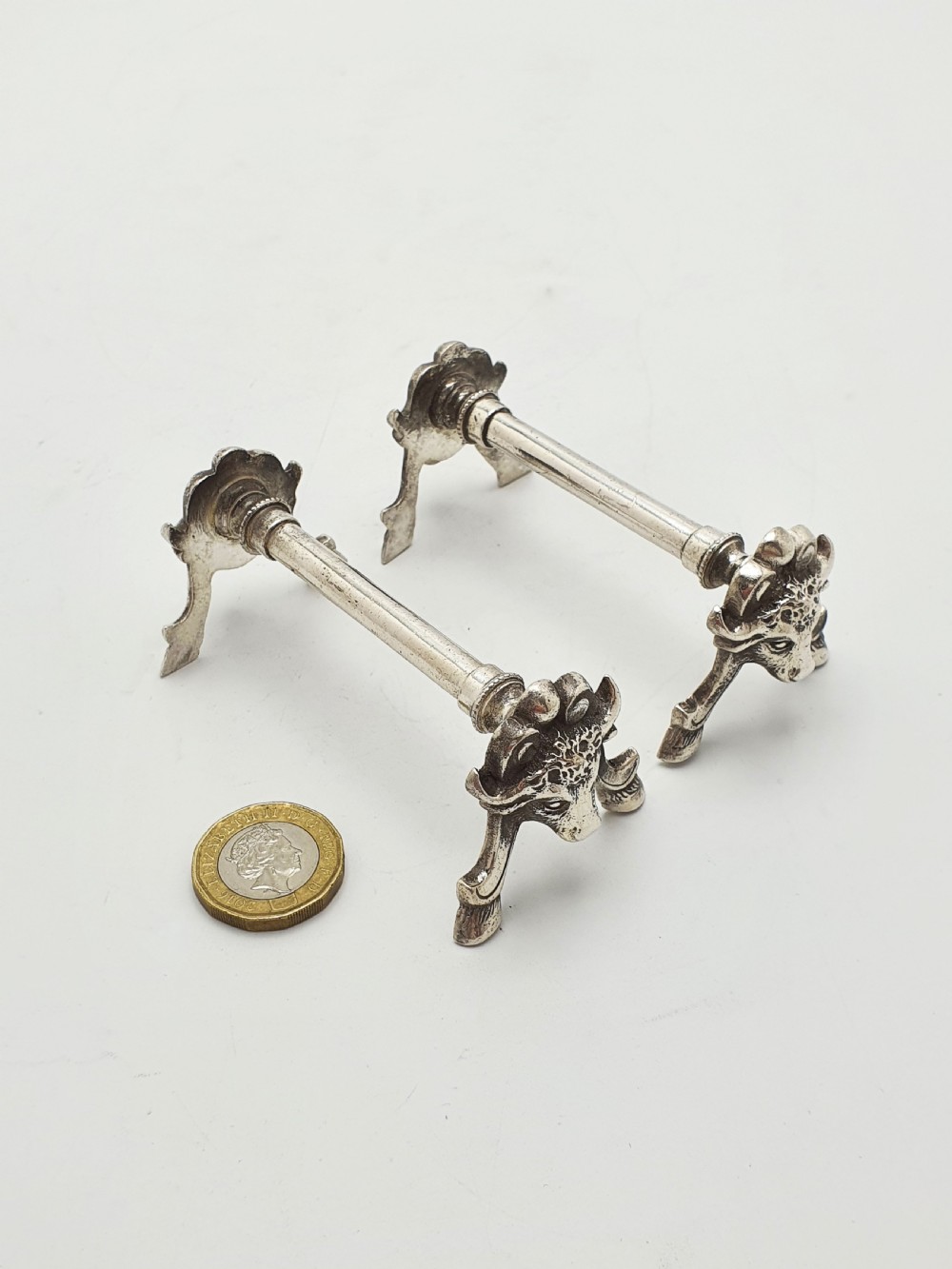 A pair of Victorian silver-plated knife rests featuring detailed cast bull head terminals with hoof legs supporting a cylindrical bar. View VI
