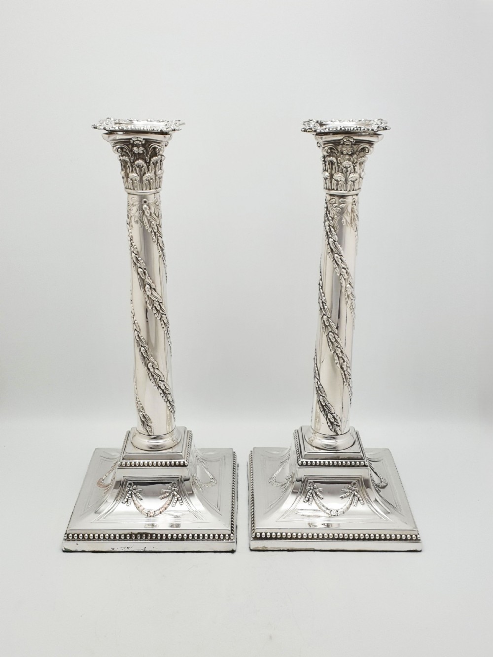 A pair of Victorian silver-plated candlesticks designed as Neoclassical Corinthian columns with spiral floral garlands and square beaded bases. View III