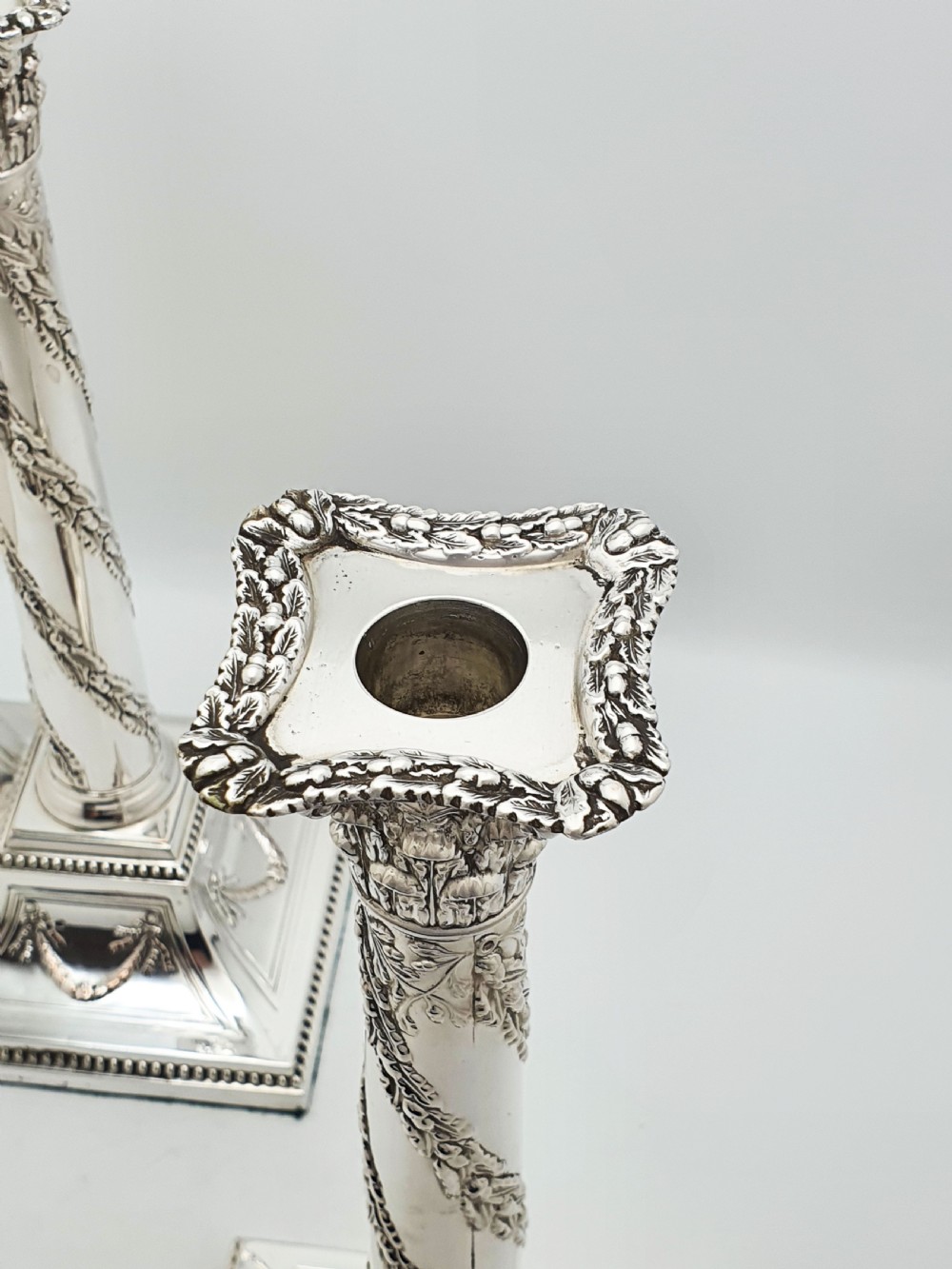 A pair of Victorian silver-plated candlesticks designed as Neoclassical Corinthian columns with spiral floral garlands and square beaded bases. View V