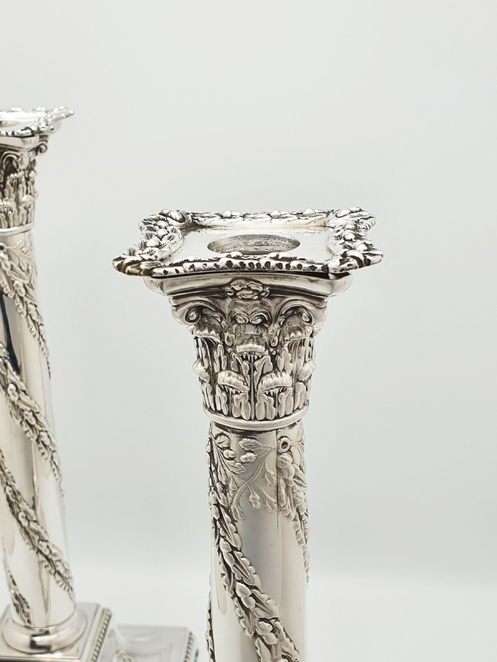A pair of Victorian silver-plated candlesticks designed as Neoclassical Corinthian columns with spiral floral garlands and square beaded bases. View VI