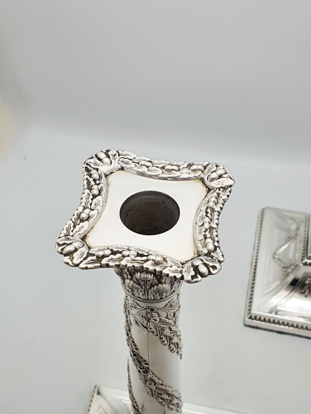 A pair of Victorian silver-plated candlesticks designed as Neoclassical Corinthian columns with spiral floral garlands and square beaded bases. View VIII