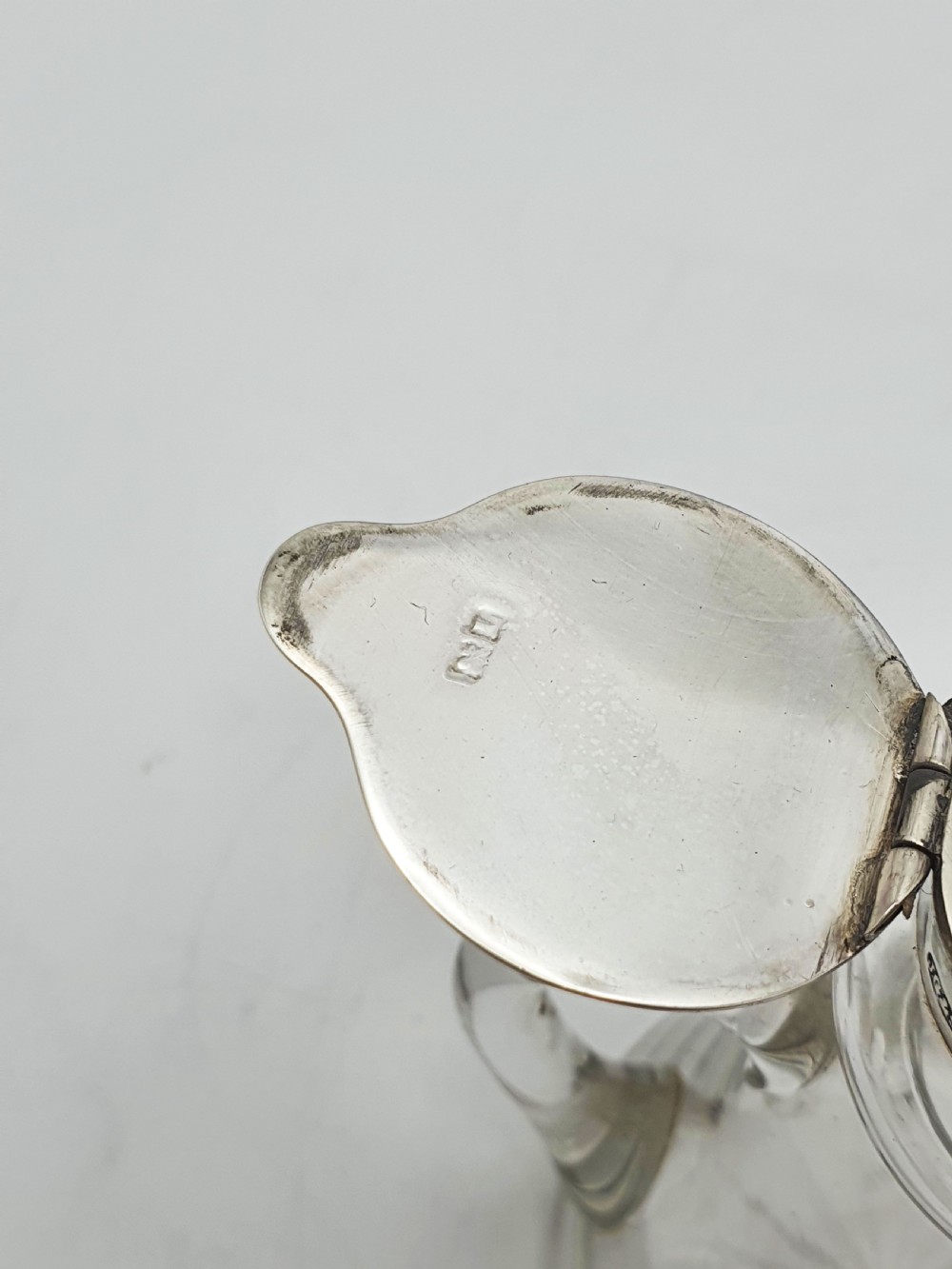 A pair of clear glass conical whiskey noggins with sterling silver collars, hinged lids, and applied glass loop handles. View VII