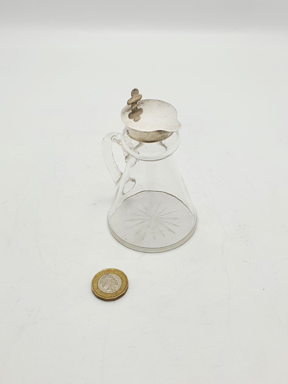 A pair of clear glass conical whiskey noggins with sterling silver collars, hinged lids, and applied glass loop handles. View XII