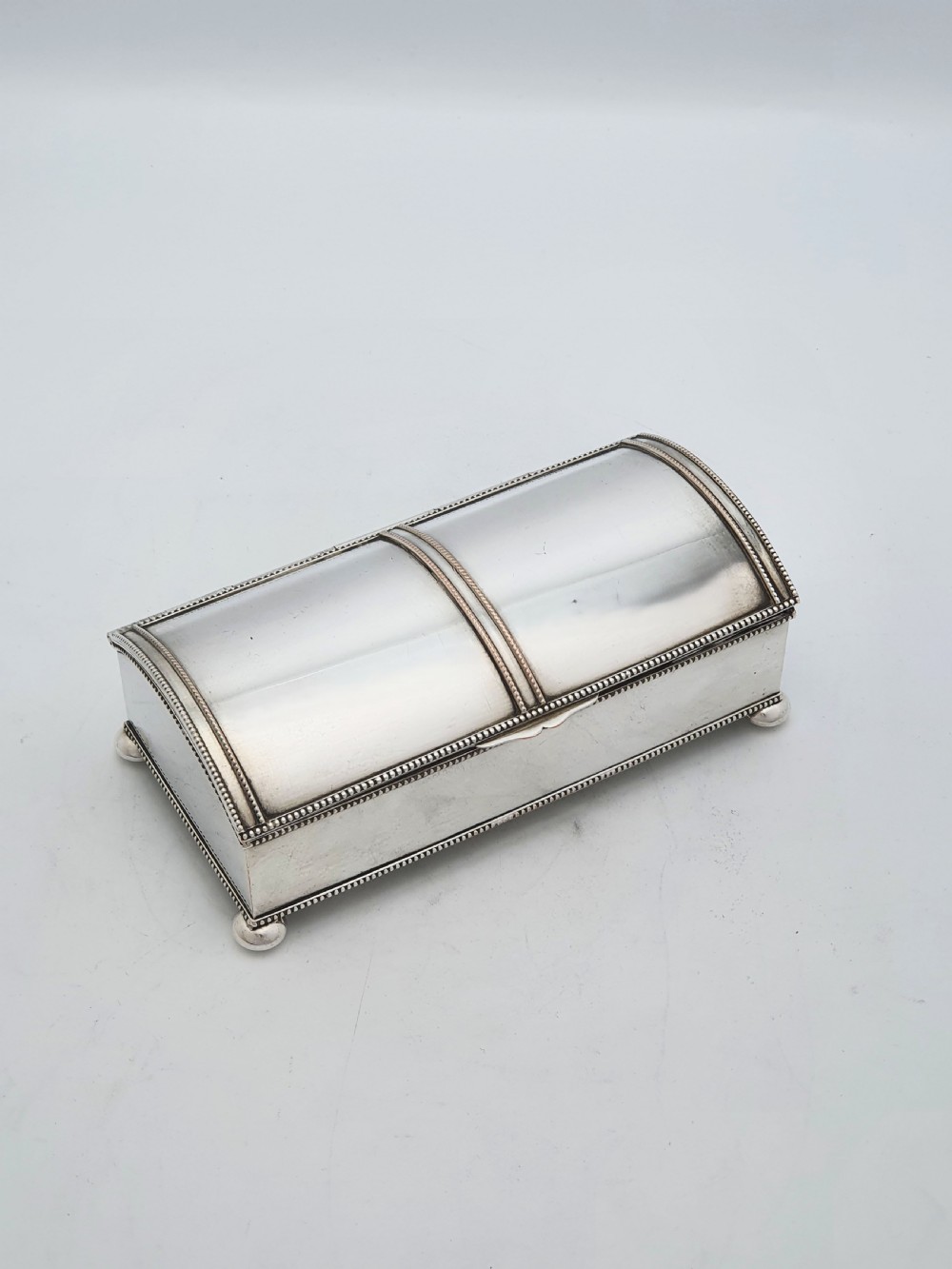 An Edwardian silver-plated rectangular inkstand box featuring a domed hinged lid, beaded border rims, and small ball feet.