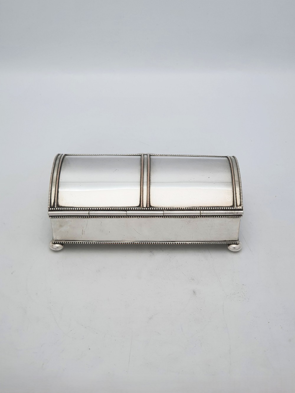 An Edwardian silver-plated rectangular inkstand box featuring a domed hinged lid, beaded border rims, and small ball feet. View VII