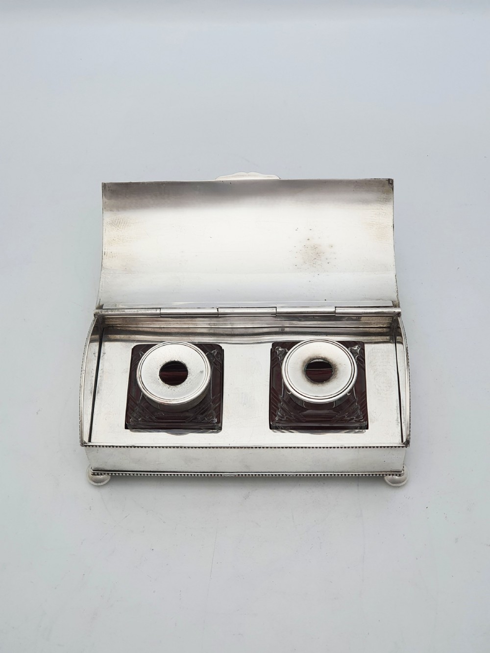 An Edwardian silver-plated rectangular inkstand box featuring a domed hinged lid, beaded border rims, and small ball feet. View X