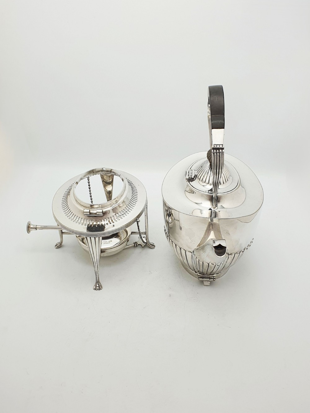 An Edwardian silver-plated spirit kettle featuring a half-fluted lower body, an ebony handle grip, and a matching tripod stand with an alcohol burner. View II
