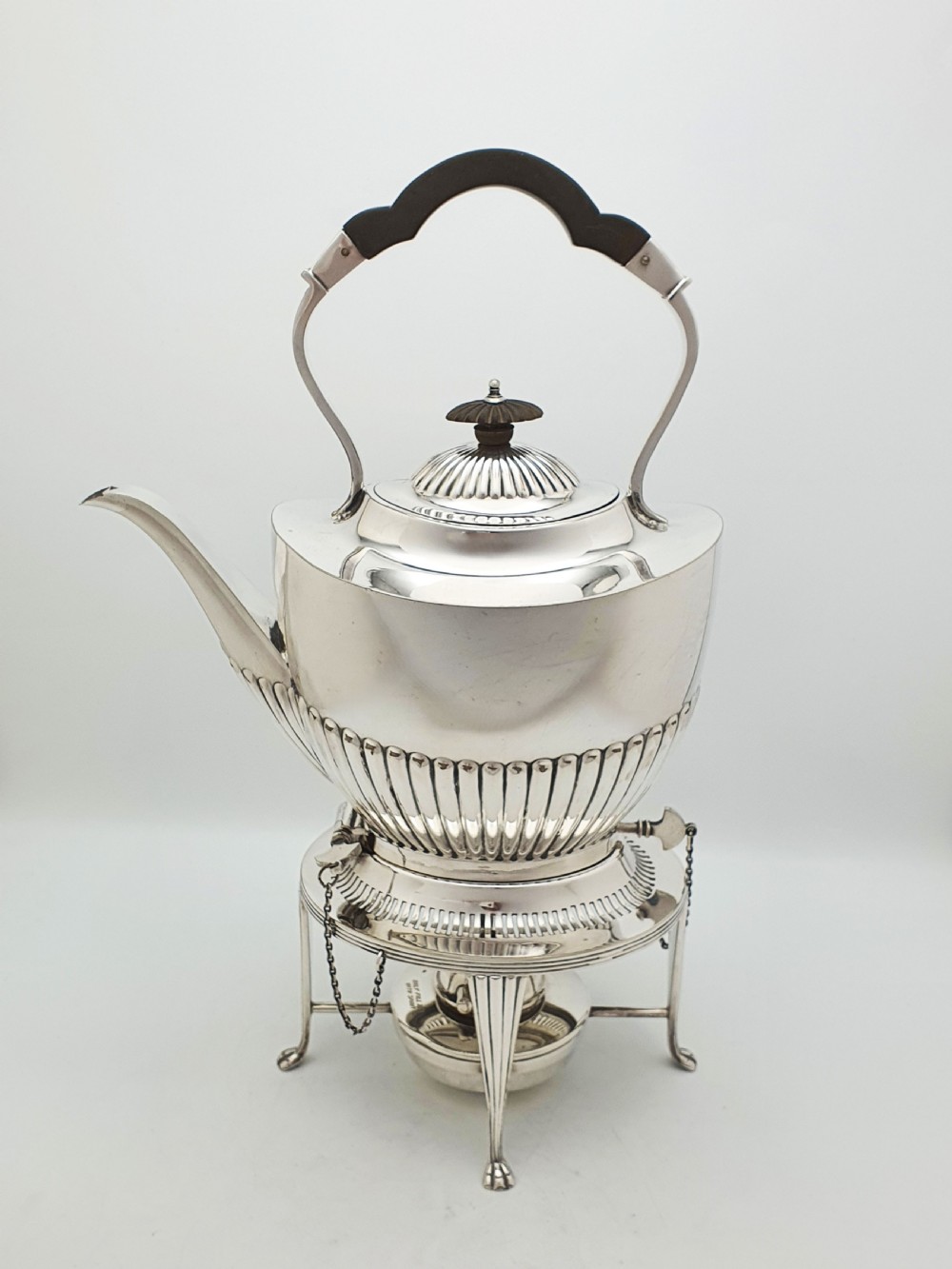 An Edwardian silver-plated spirit kettle featuring a half-fluted lower body, an ebony handle grip, and a matching tripod stand with an alcohol burner. View III