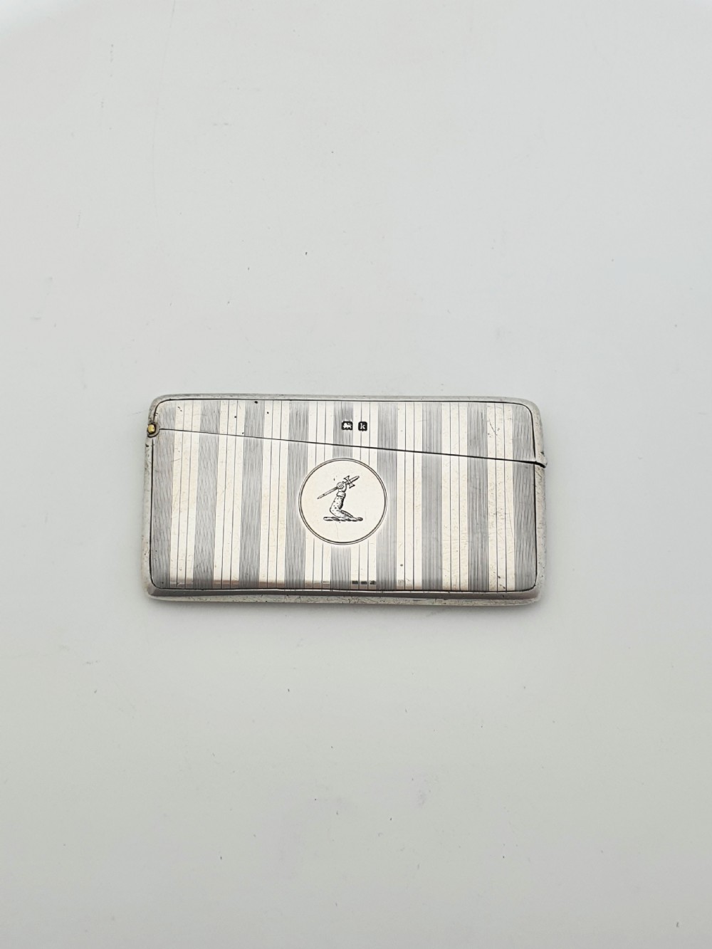An open Edwardian sterling silver card box featuring an engine-turned striped pattern, British hallmarks, and an engraved central crest. View II