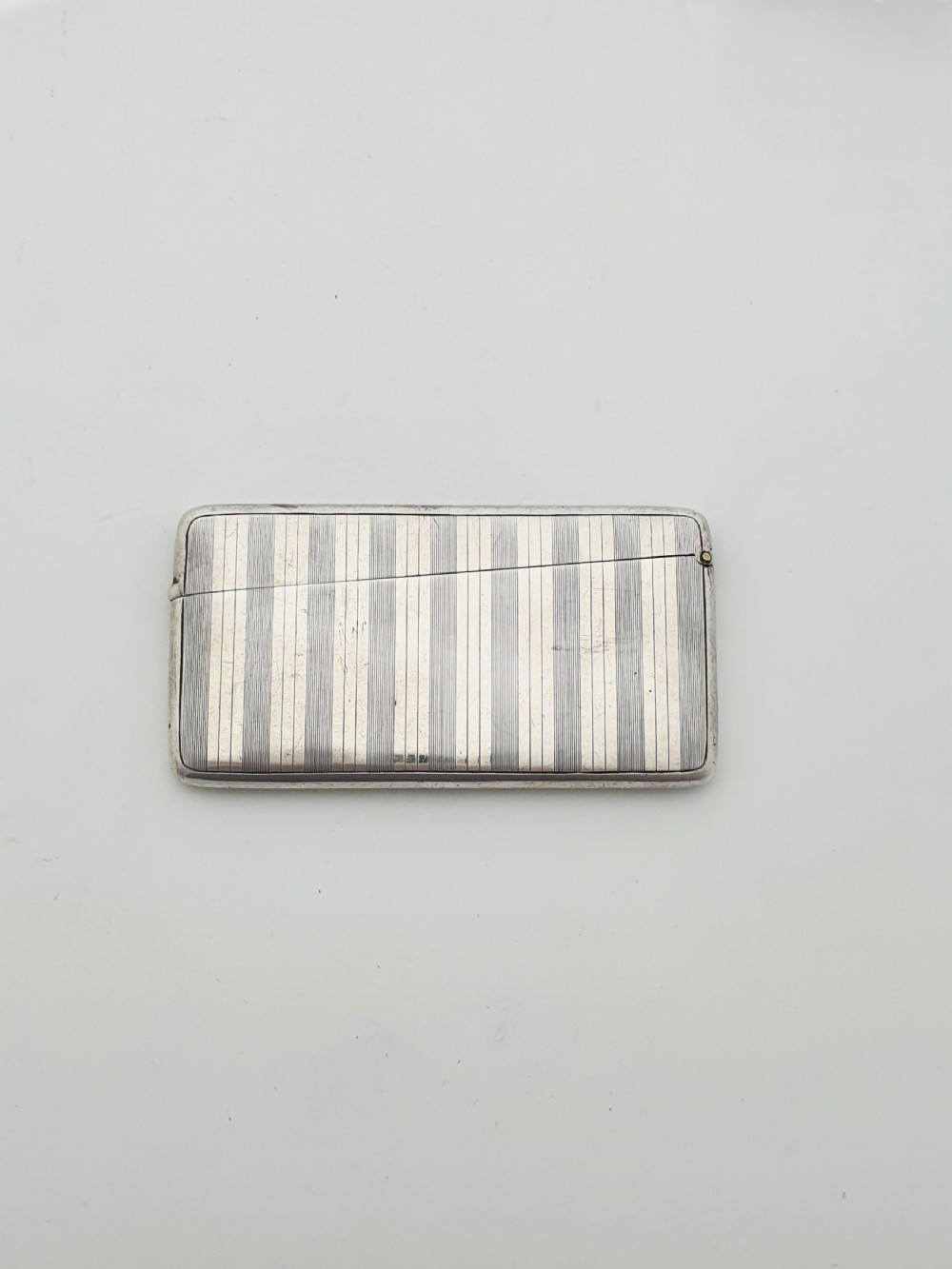 An open Edwardian sterling silver card box featuring an engine-turned striped pattern, British hallmarks, and an engraved central crest. View III