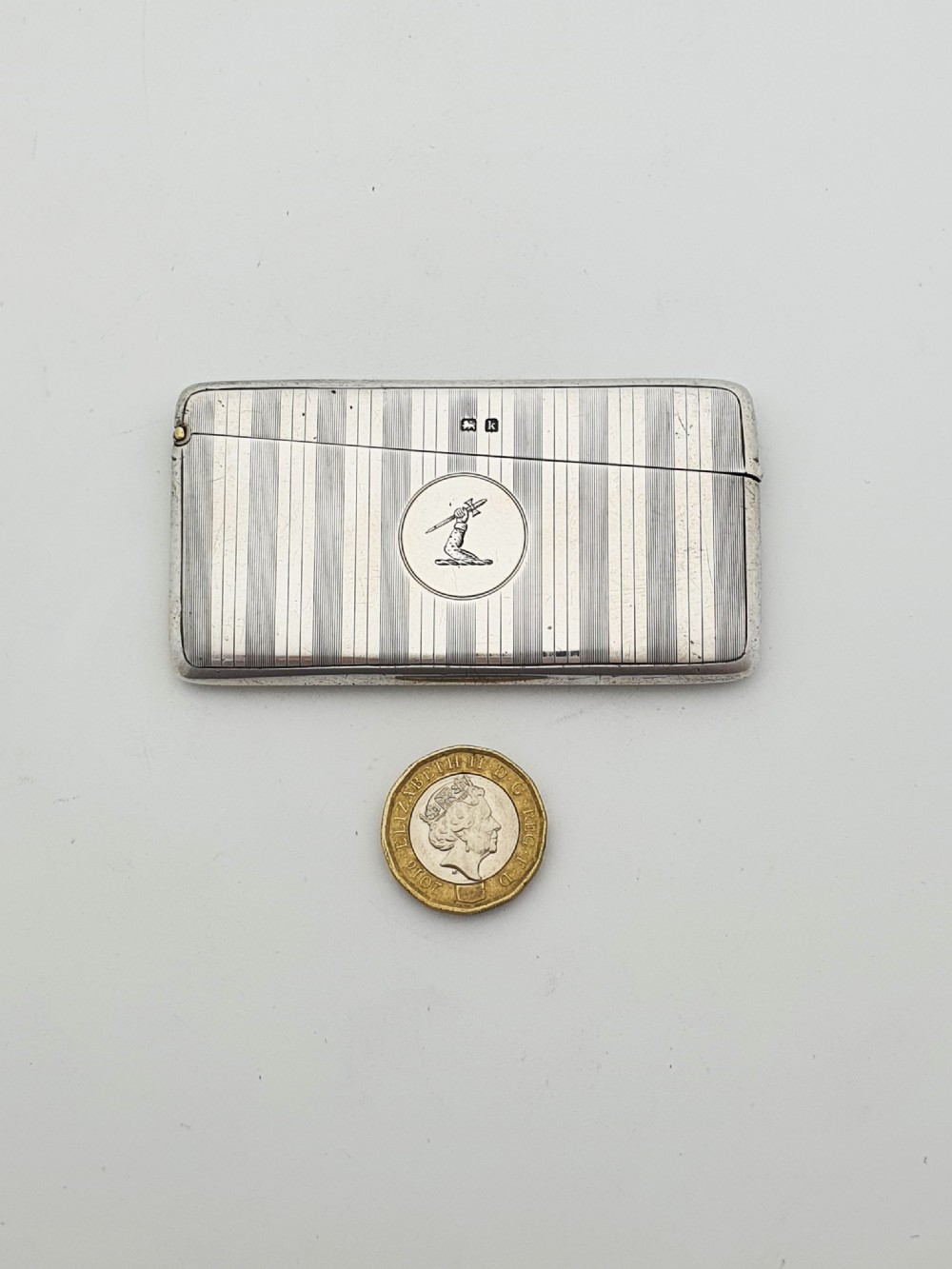 An open Edwardian sterling silver card box featuring an engine-turned striped pattern, British hallmarks, and an engraved central crest. View VIII