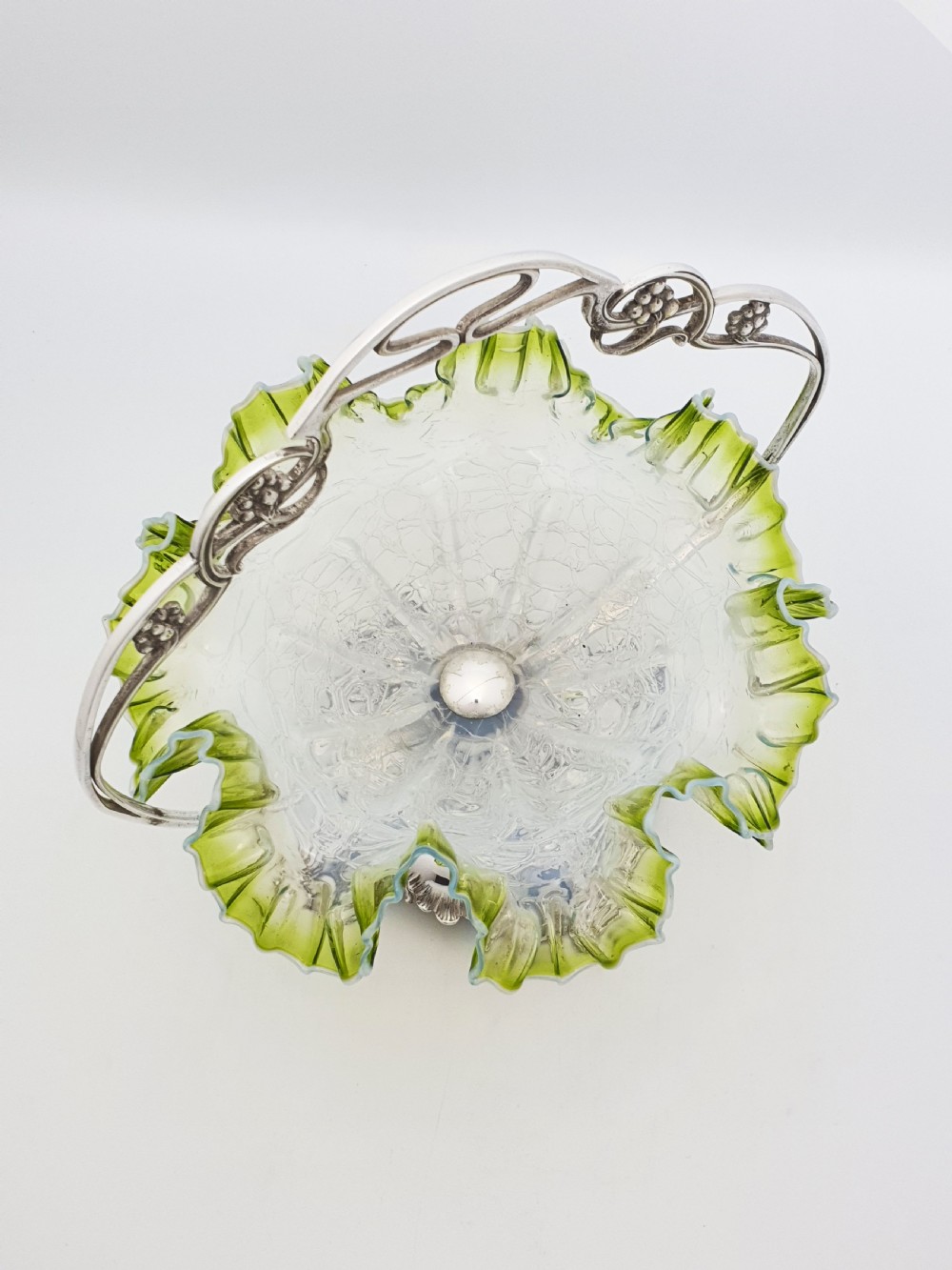 An Art Nouveau silver-plated centrepiece frame with an arched handle holding a frilled green-rimmed vaseline glass dish with a crackle texture. View III