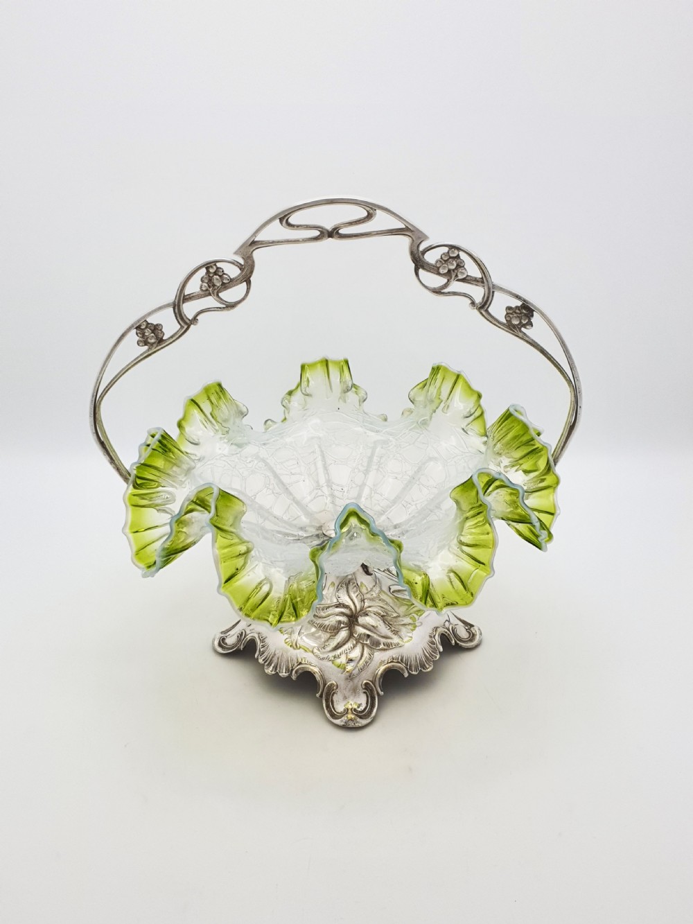 An Art Nouveau silver-plated centrepiece frame with an arched handle holding a frilled green-rimmed vaseline glass dish with a crackle texture. View VI